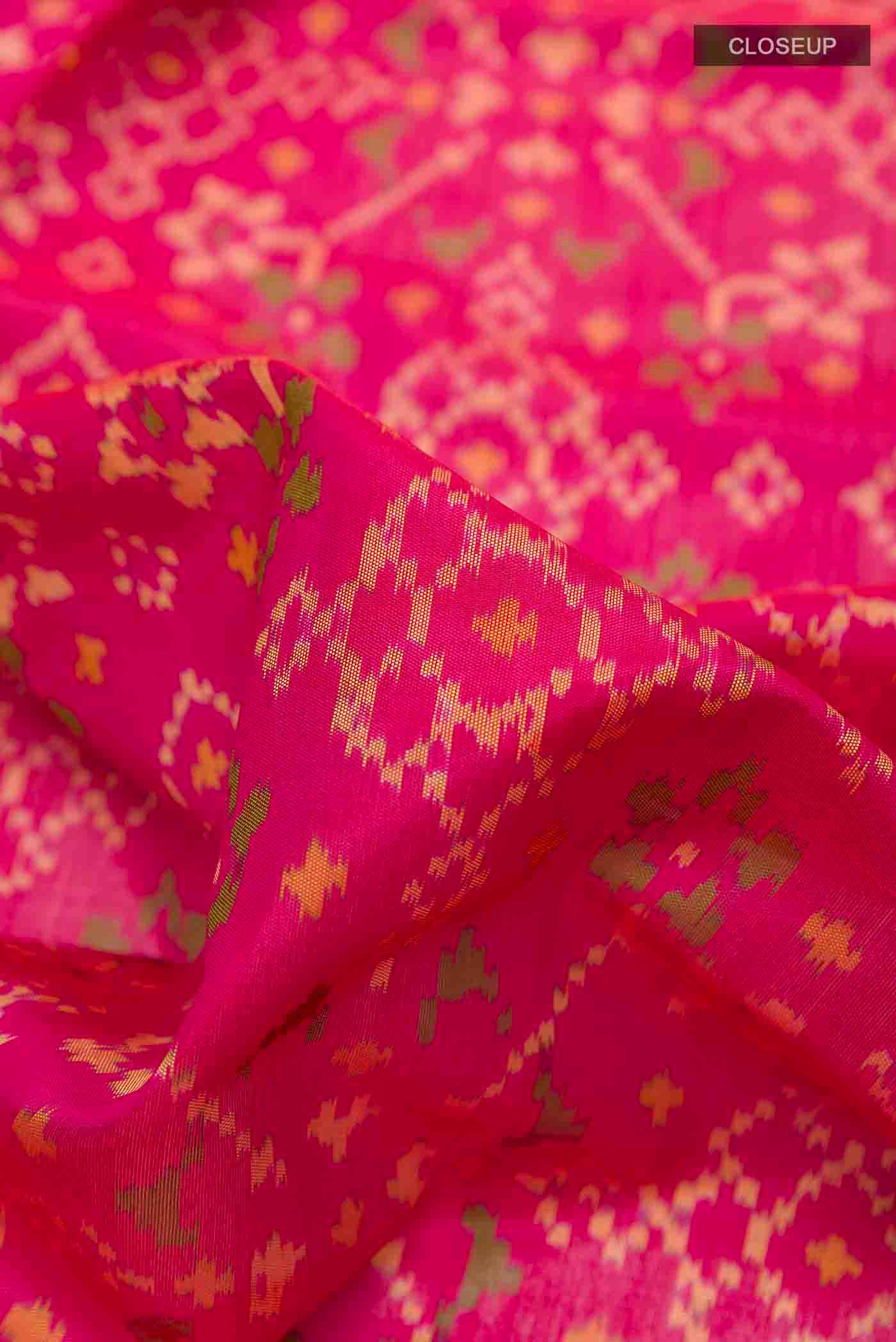 Close up of Pink Rajkot Patola Silk Saree with Ikat design on the body and Zari Border displaying folds