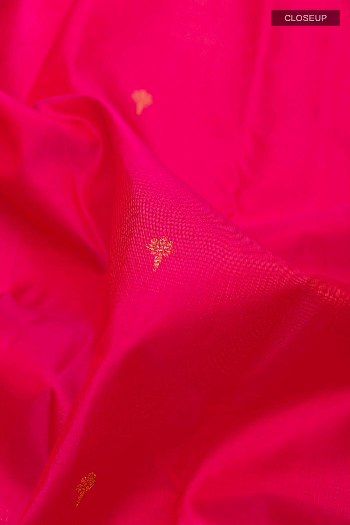 Close up of Pink Kanchipuram Silk Saree with Zari Butta on the body and Zari Border displaying folds