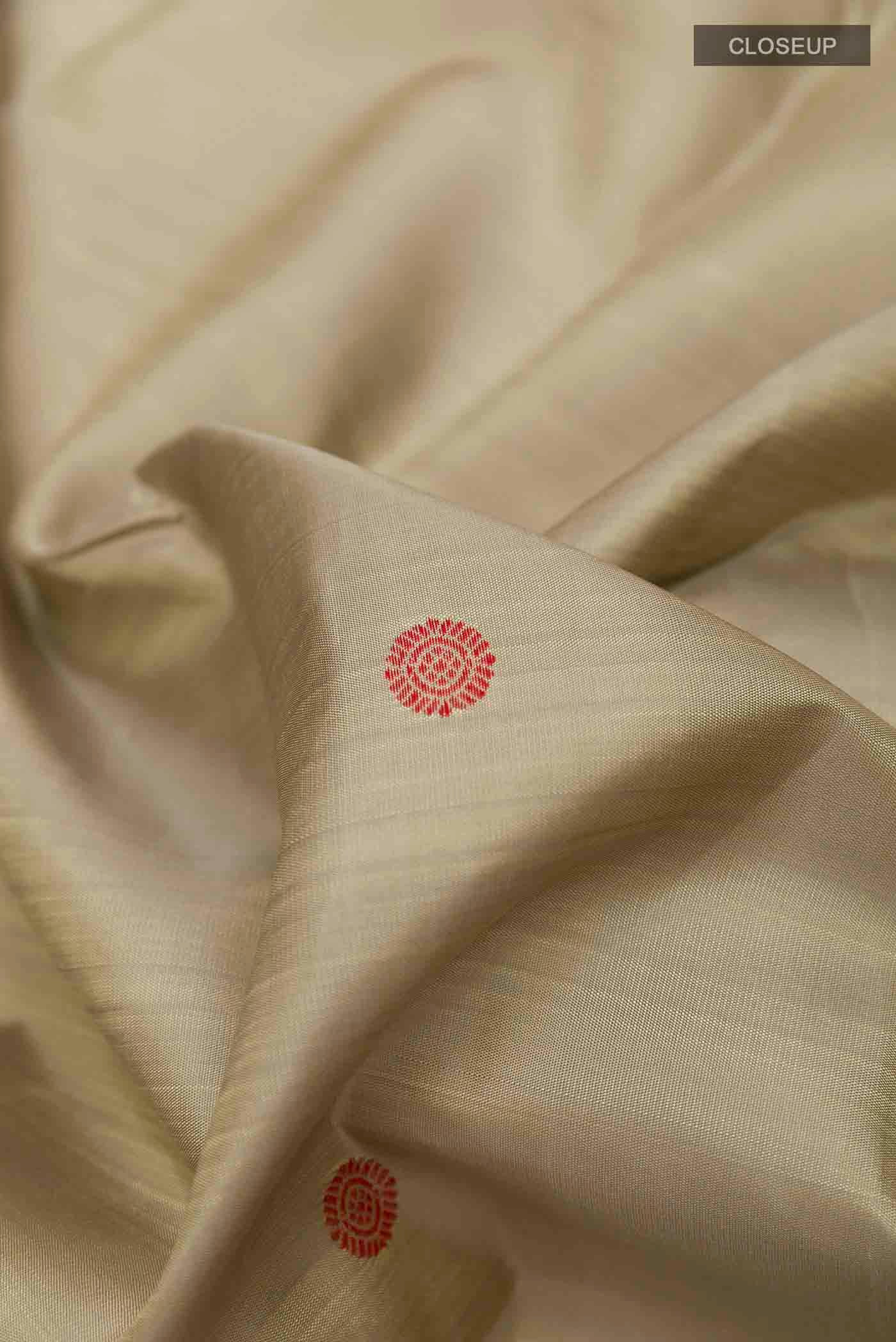 Close up of Beige Kanchipuram Silk Saree with Thread Butta on the body and Thread Border displaying folds