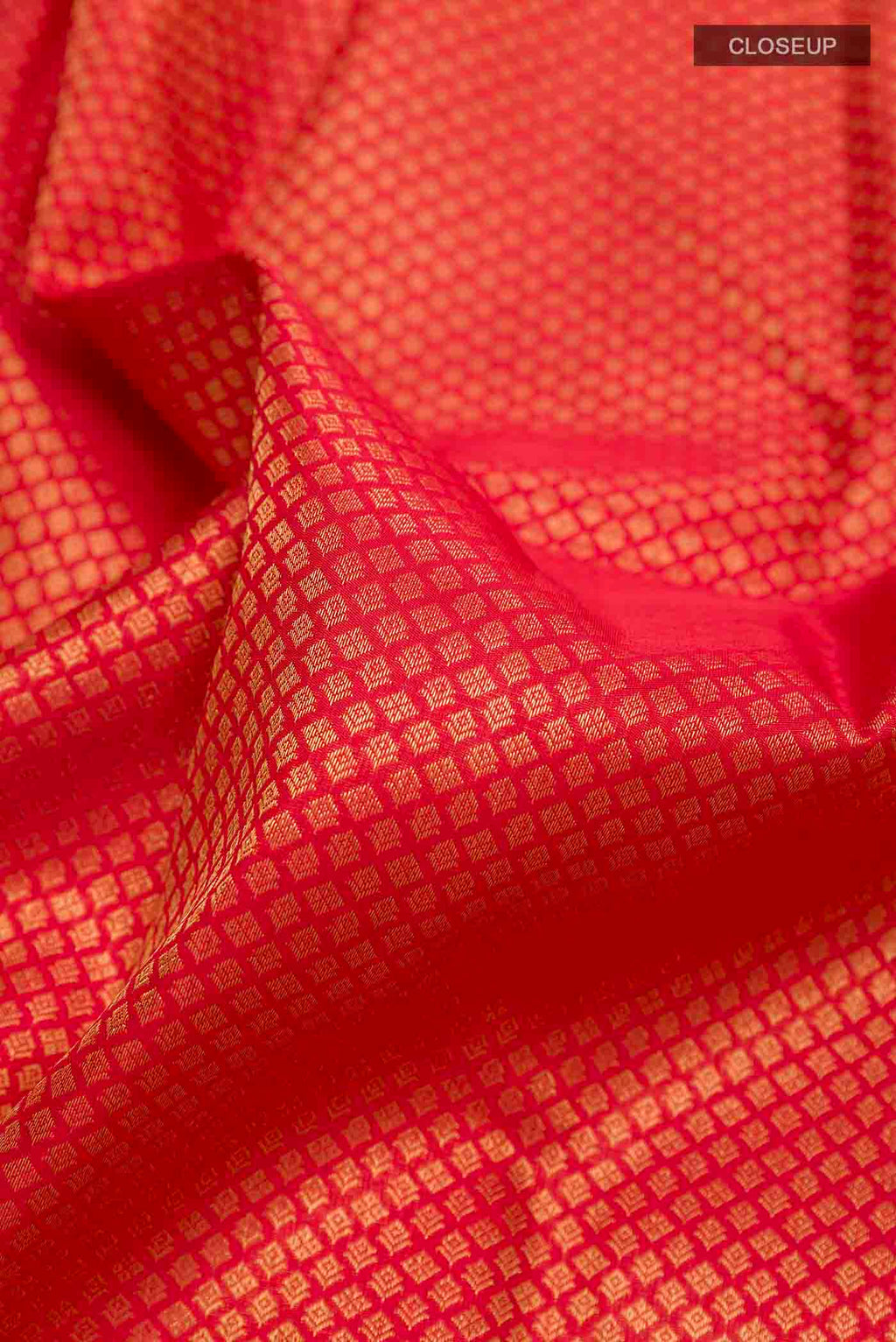 Close up of Pure Silk Pure Zari Red Kanchipuram Saree with Zari Butta on the body and Zari Border displaying folds