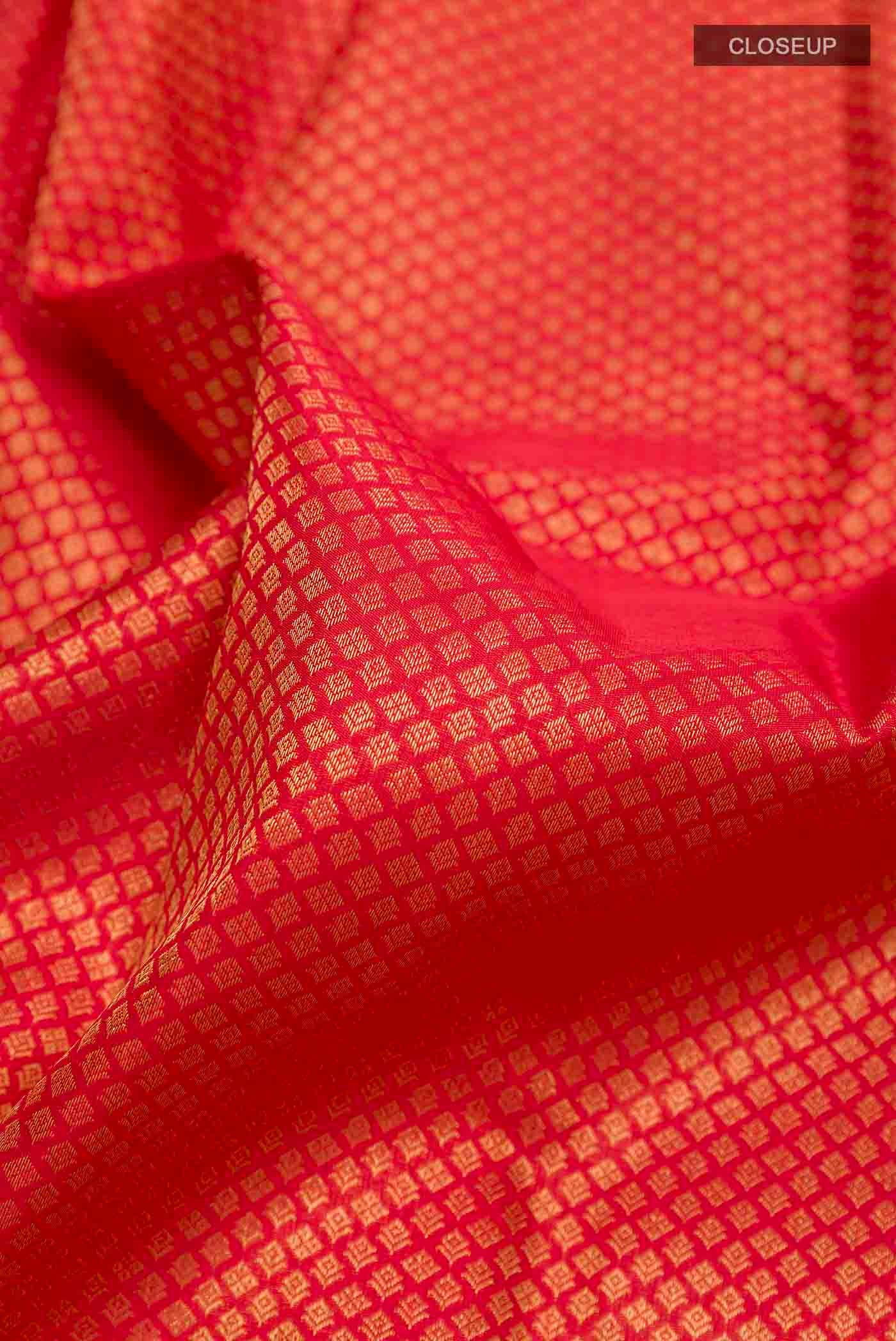 Close up of Pure Silk Pure Zari Red Kanchipuram Saree with Zari Butta on the body and Zari Border displaying folds