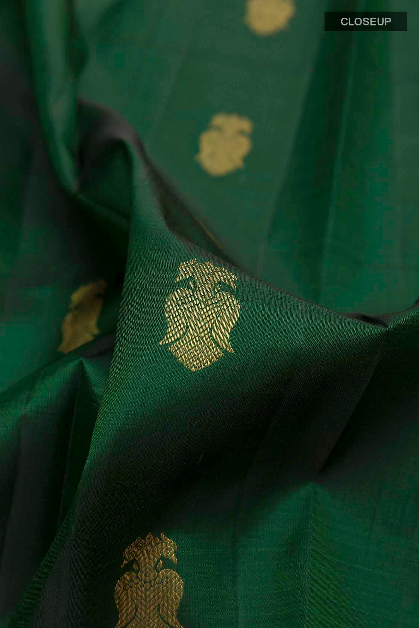 Close up of Green Kanchipuram Silk Saree with Zari Butta on the body and Zari Border displaying folds