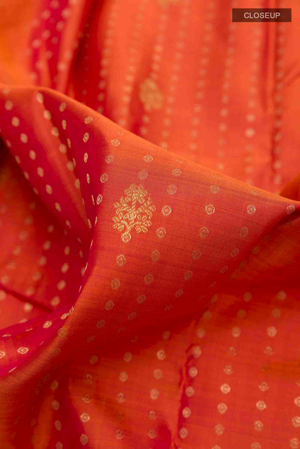 Close up of Orange Kanchipuram Silk Saree with Zari Butta on the body and Zari Border displaying folds