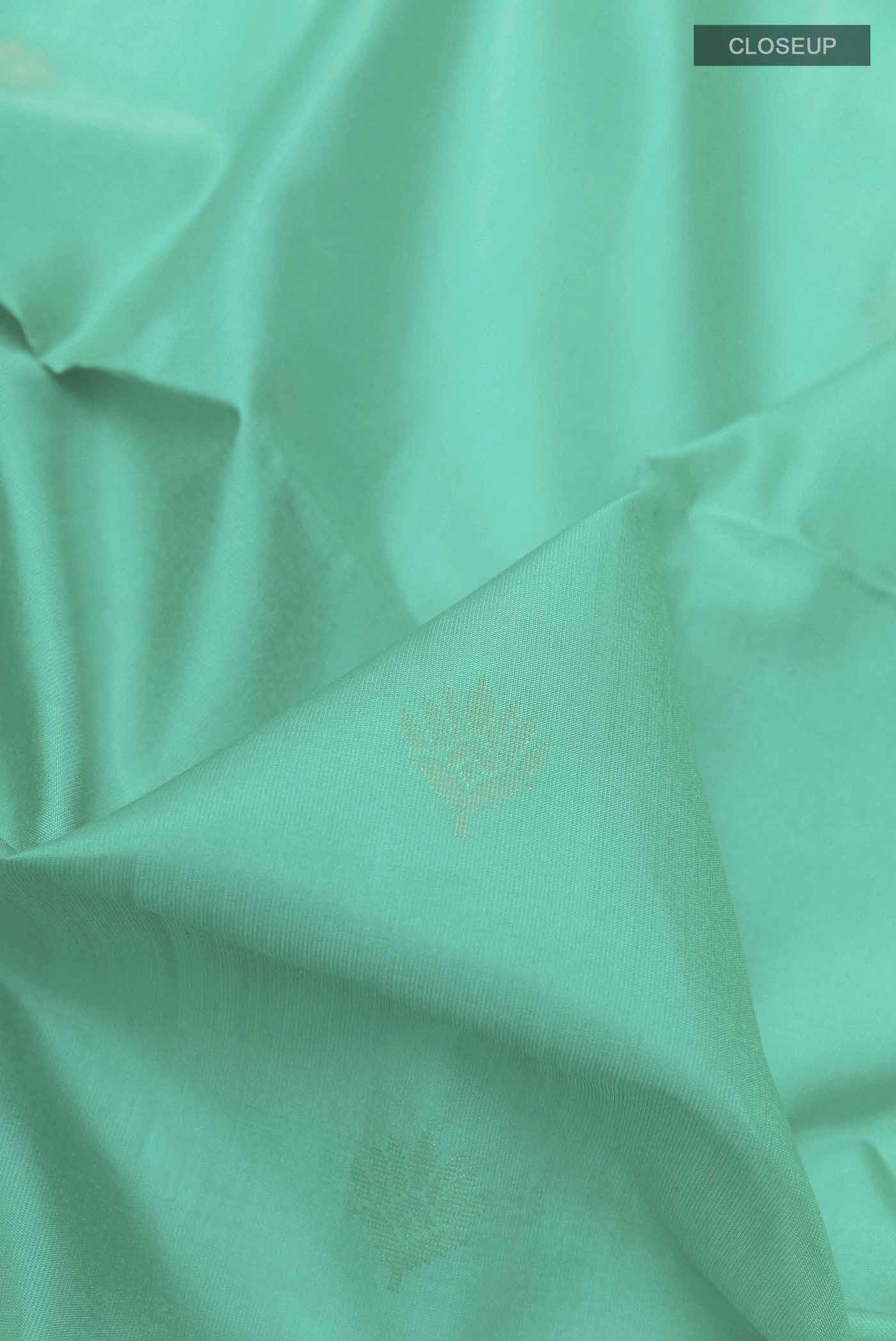 Close up of Sea Green Soft Silk Saree with Zari Butta on the body and Zari Border displaying folds