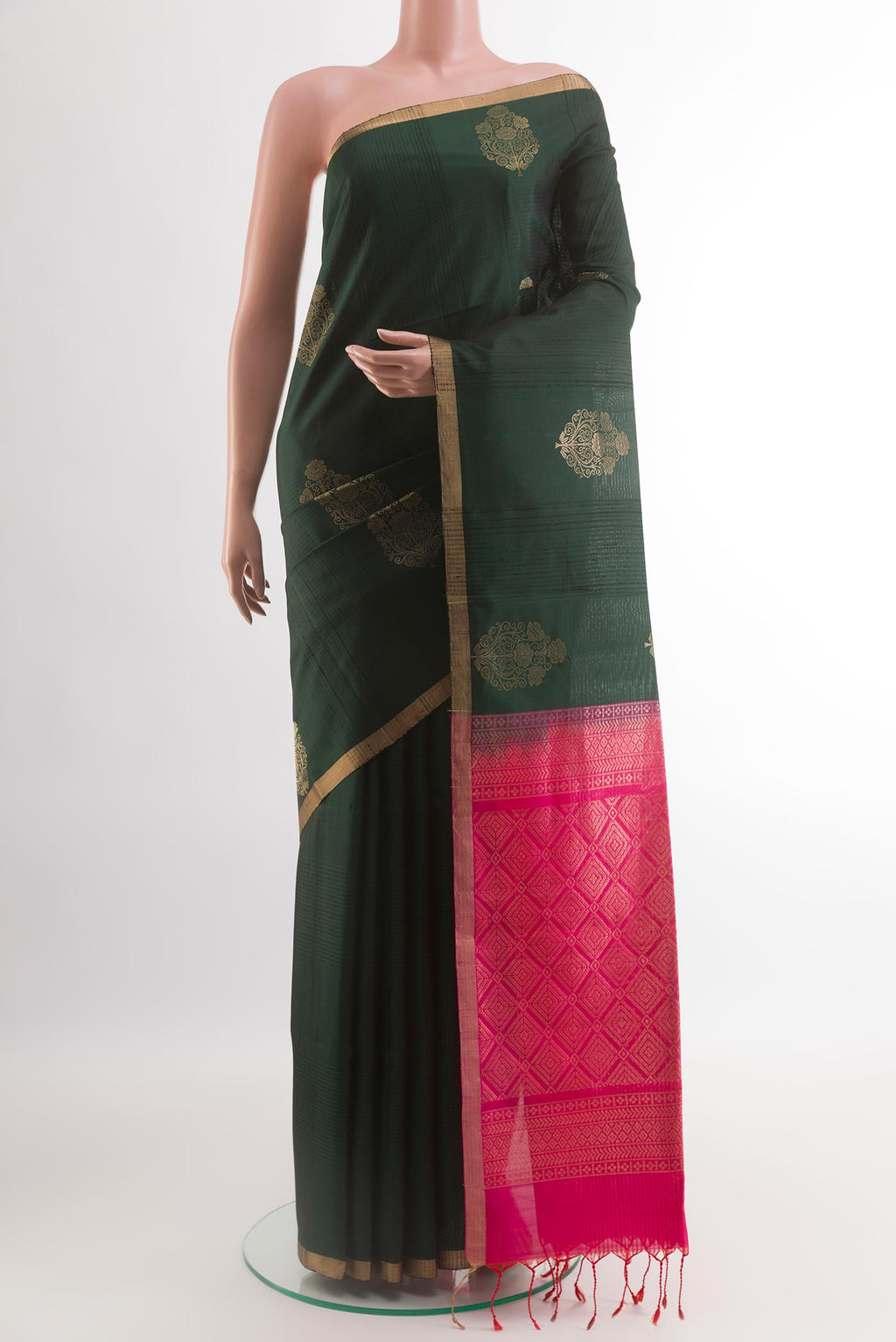 Bottle Green Soft Silk Saree with Zari Butta on the body and Zari Border.  displayed on a mannequin