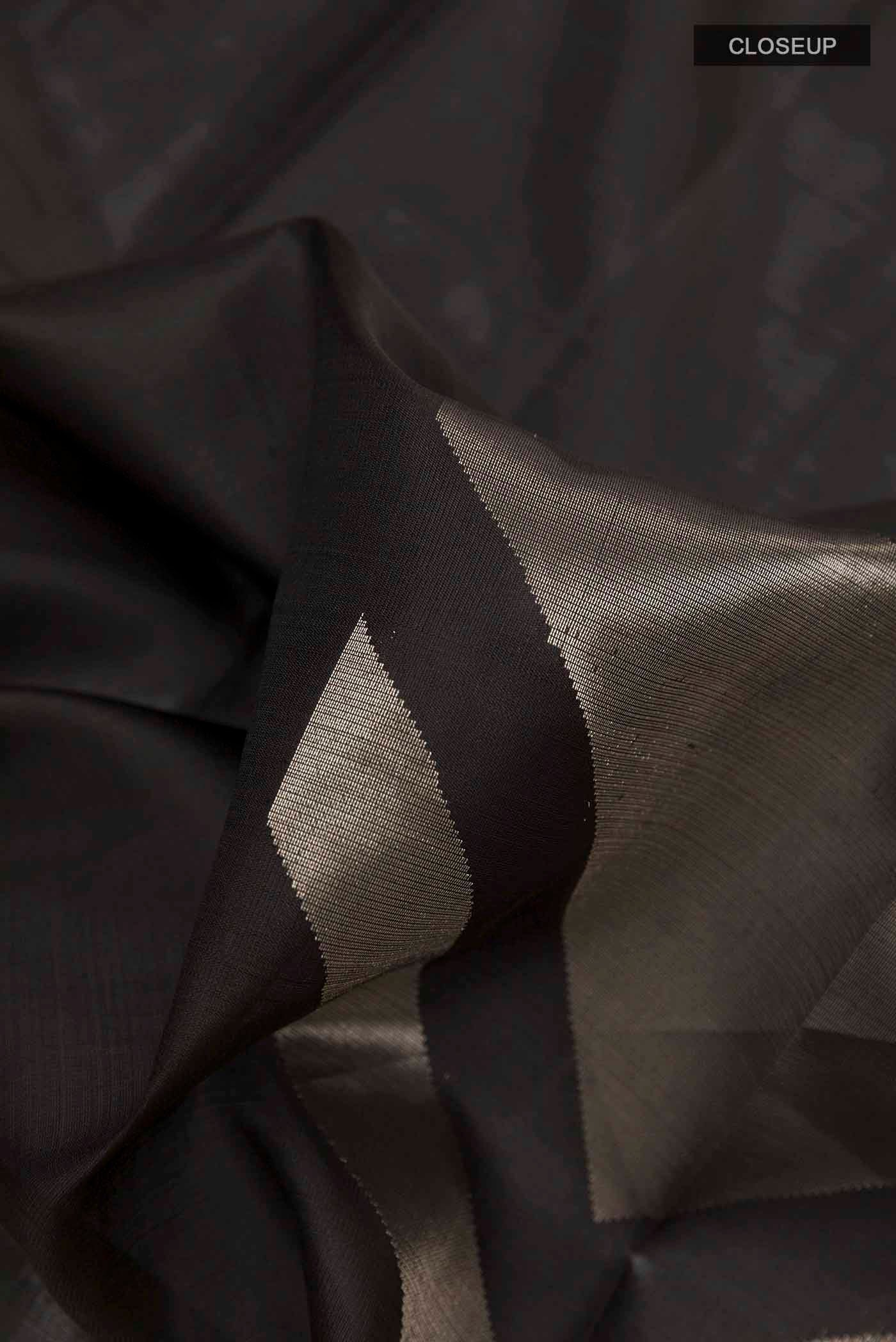 Close up of Black Soft Silk Saree with Zari Butta on the body and Zari Border displaying folds