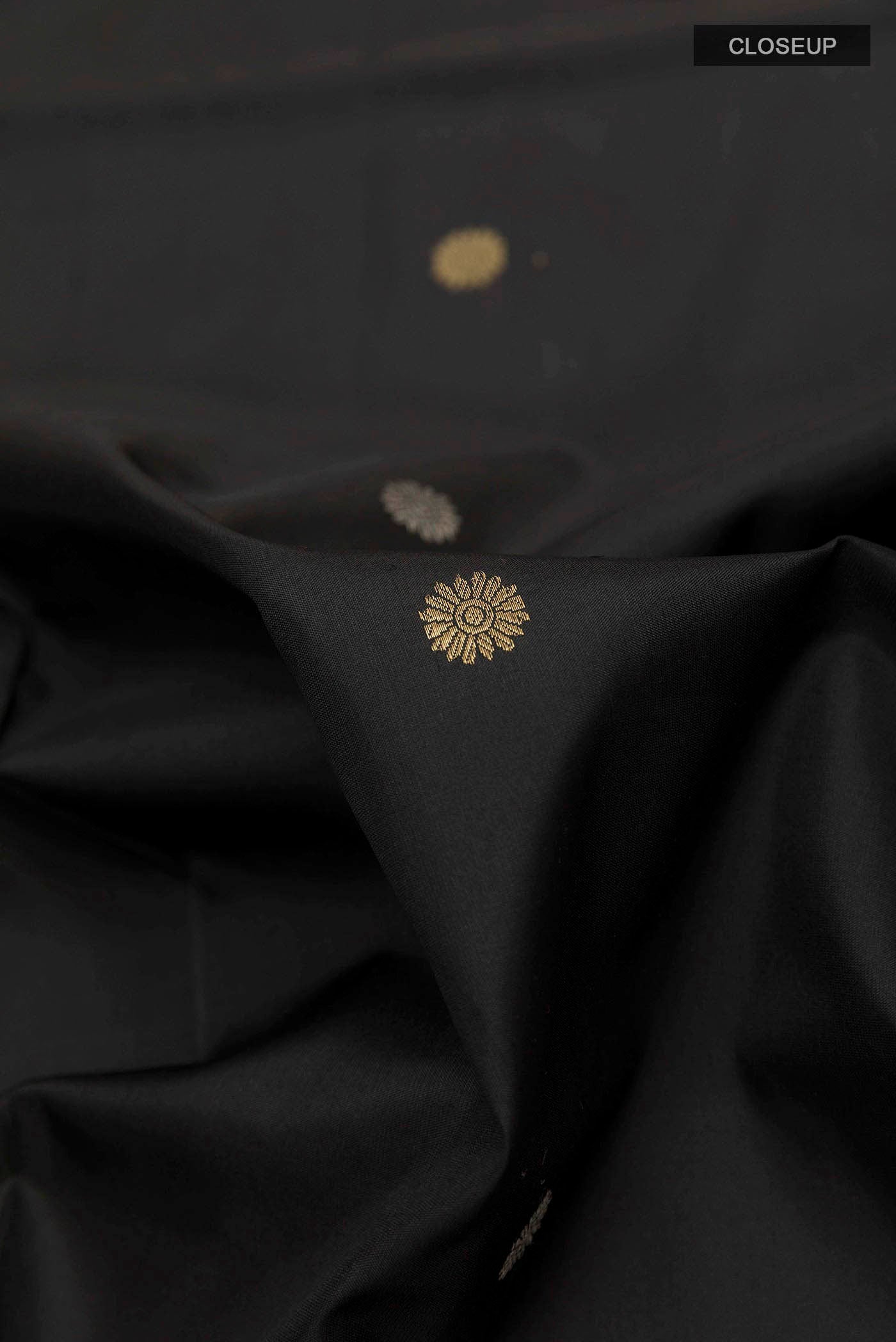 Close up of Black Soft Silk Saree with Zari Butta on the body and Zari Border displaying folds