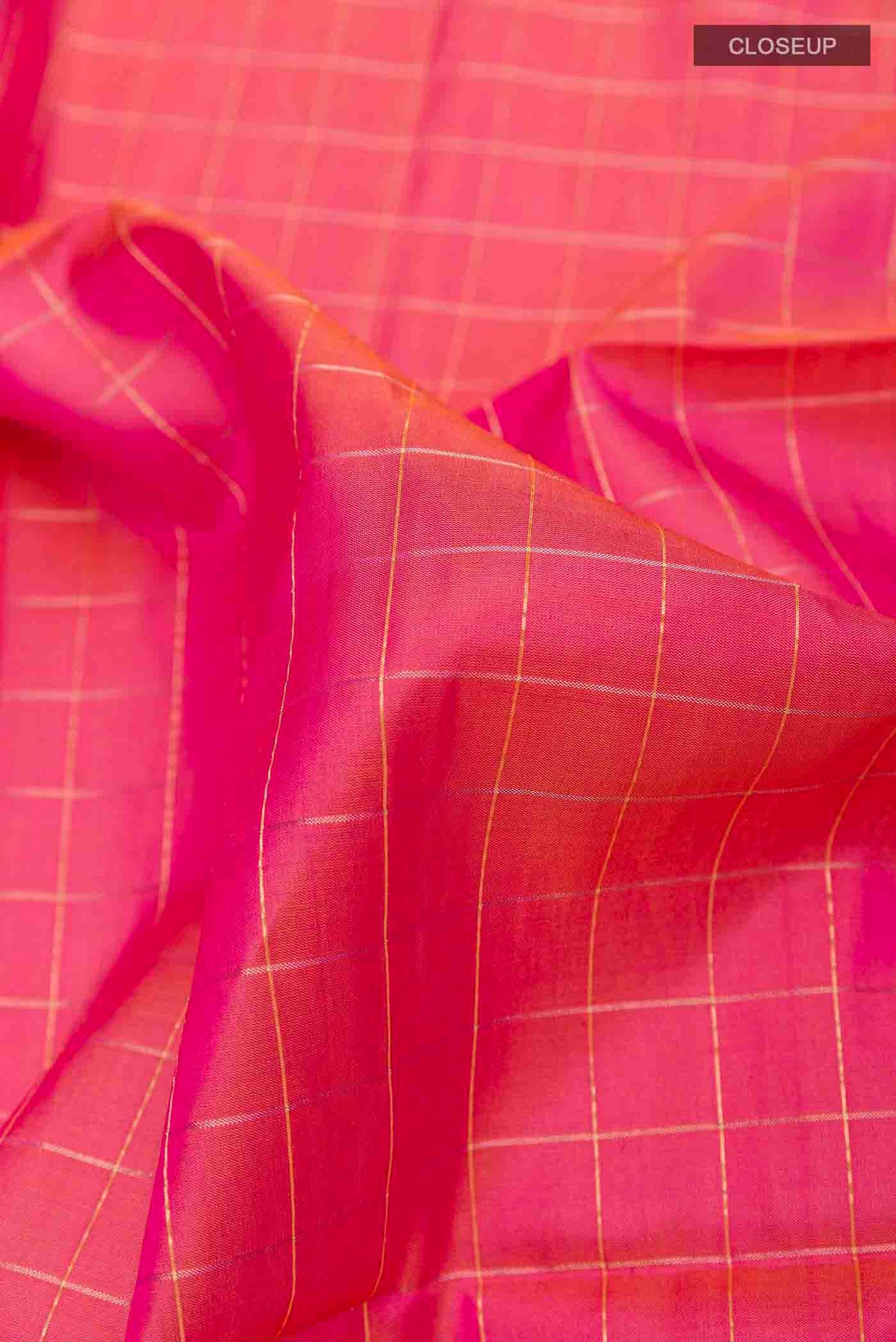Close up of Peach Soft Silk Saree with Checked design on the body and Zari Border displaying folds