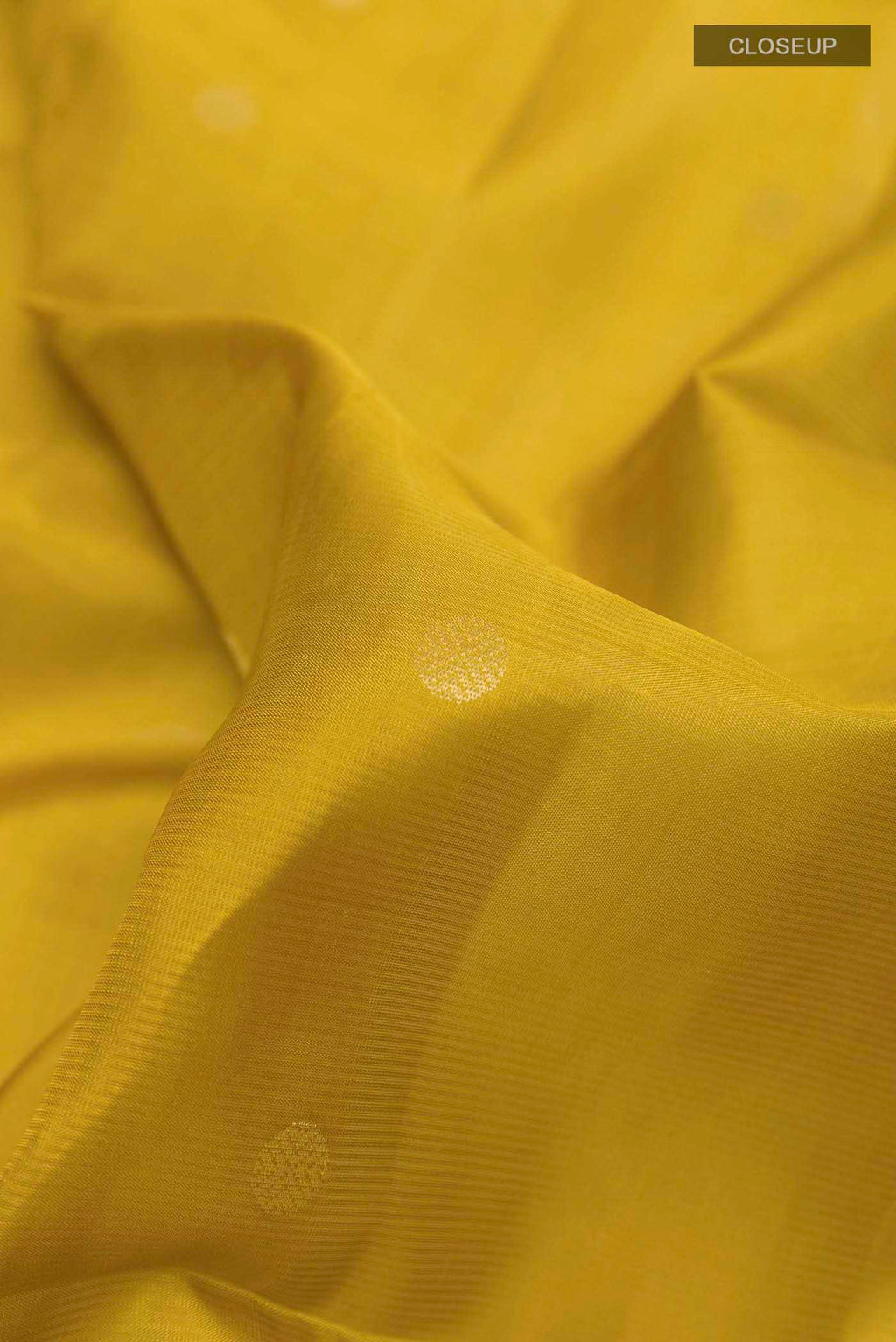 Close up of Yellow Soft Silk Saree with Zari Butta on the body and Zari Border displaying folds