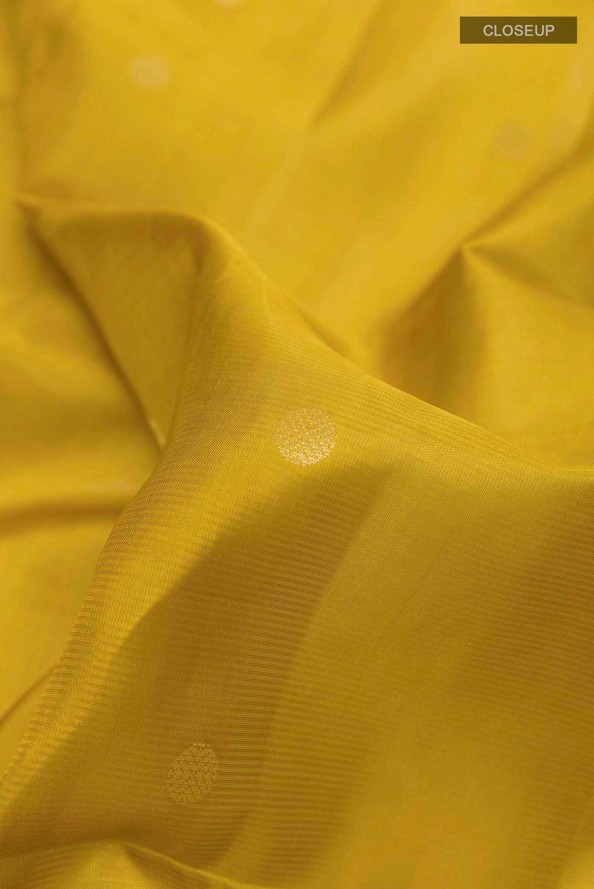 Close up of Yellow Soft Silk Saree with Zari Butta on the body and Zari Border displaying folds