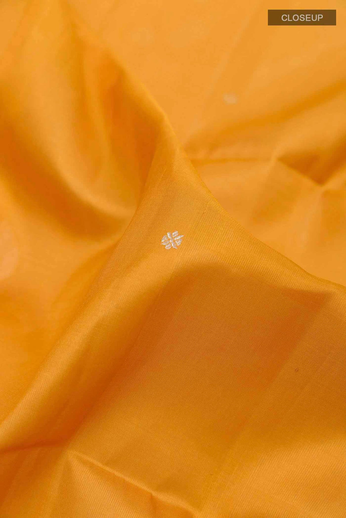 Close up of Mustard Soft Silk Saree with Zari Butta on the body and Zari Border displaying folds