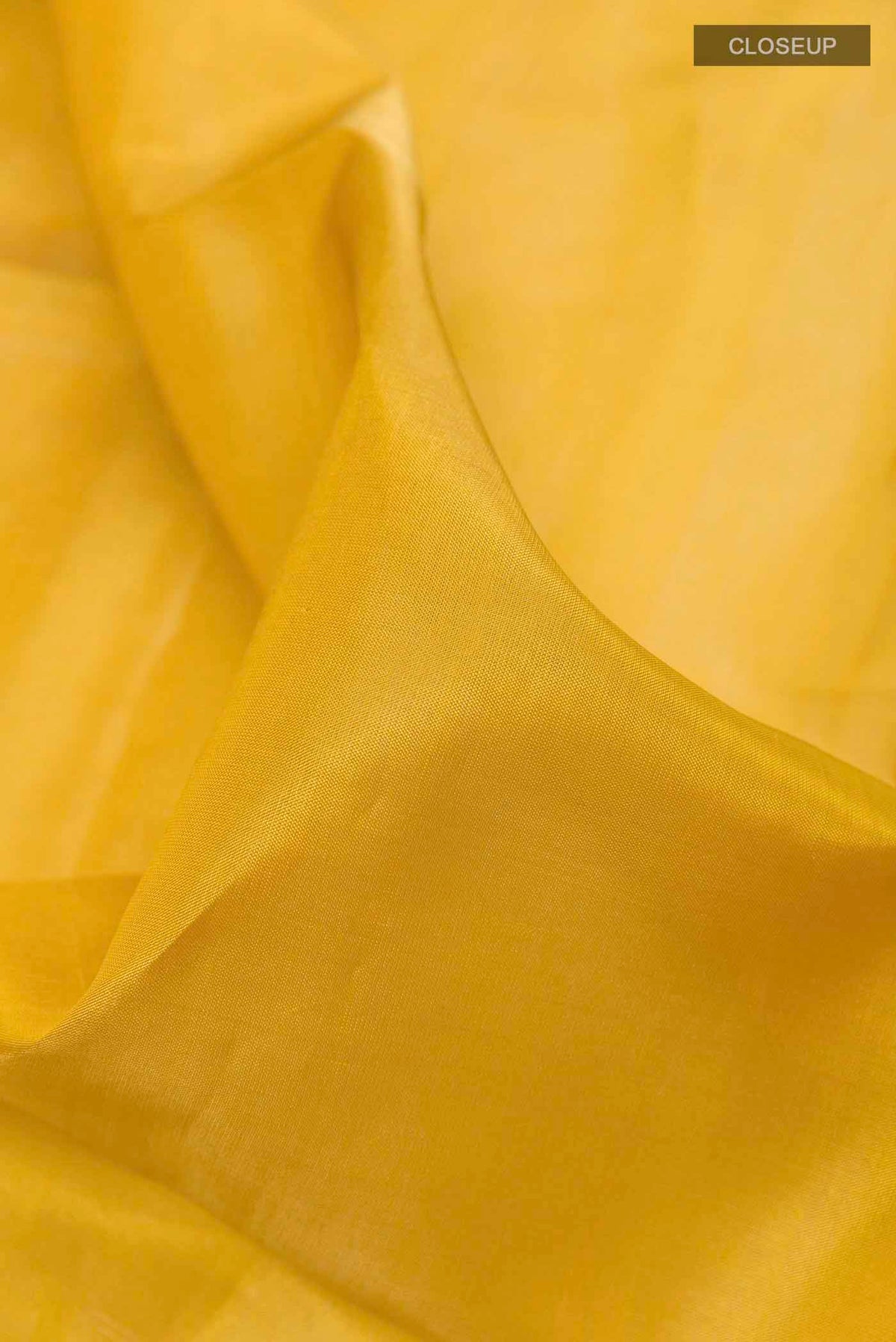 Close up of Yellow Soft Silk Saree with Plain Body and Zari Border displaying folds