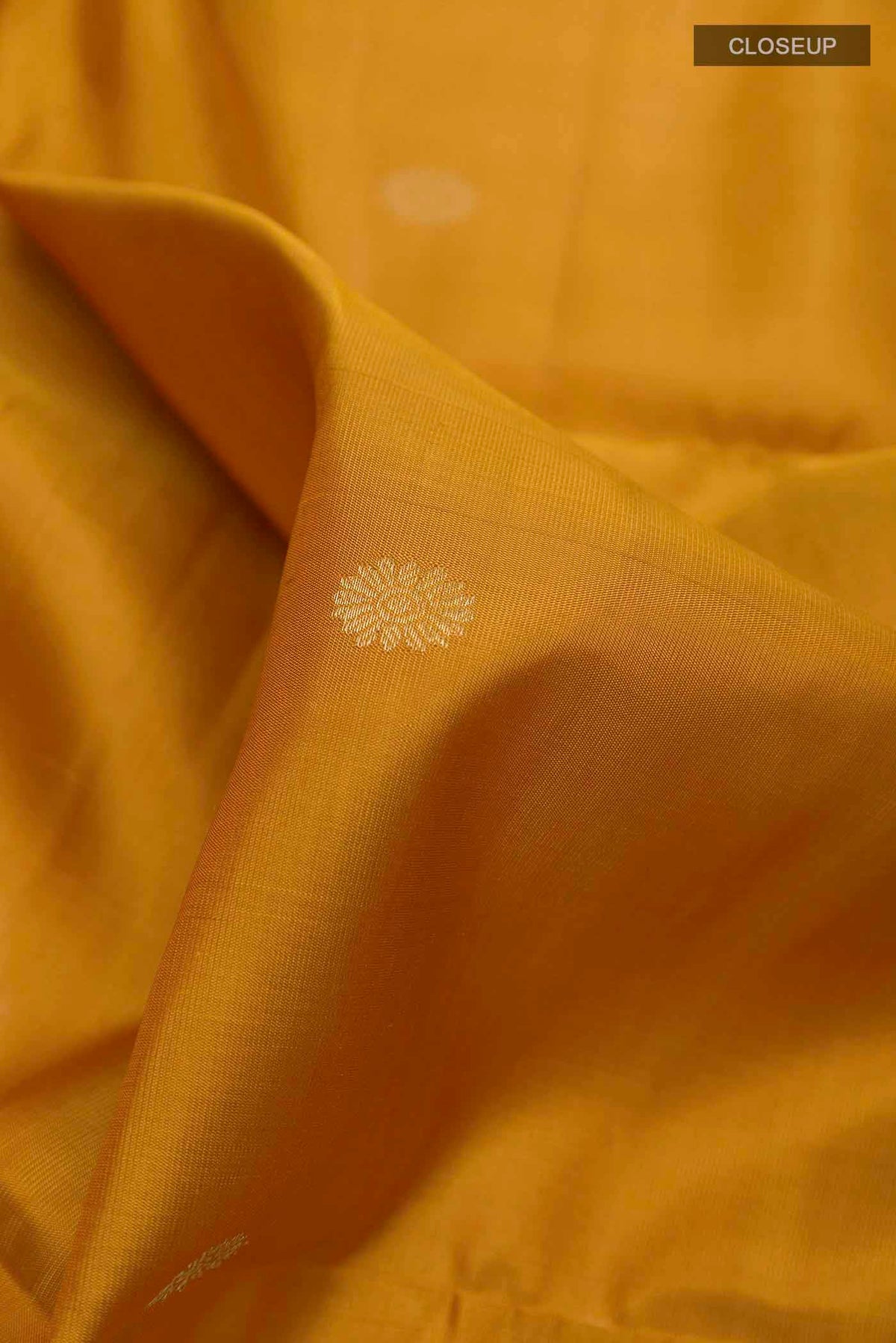Close up of Yellow Soft Silk Saree with Zari Butta on the body and Zari Border displaying folds