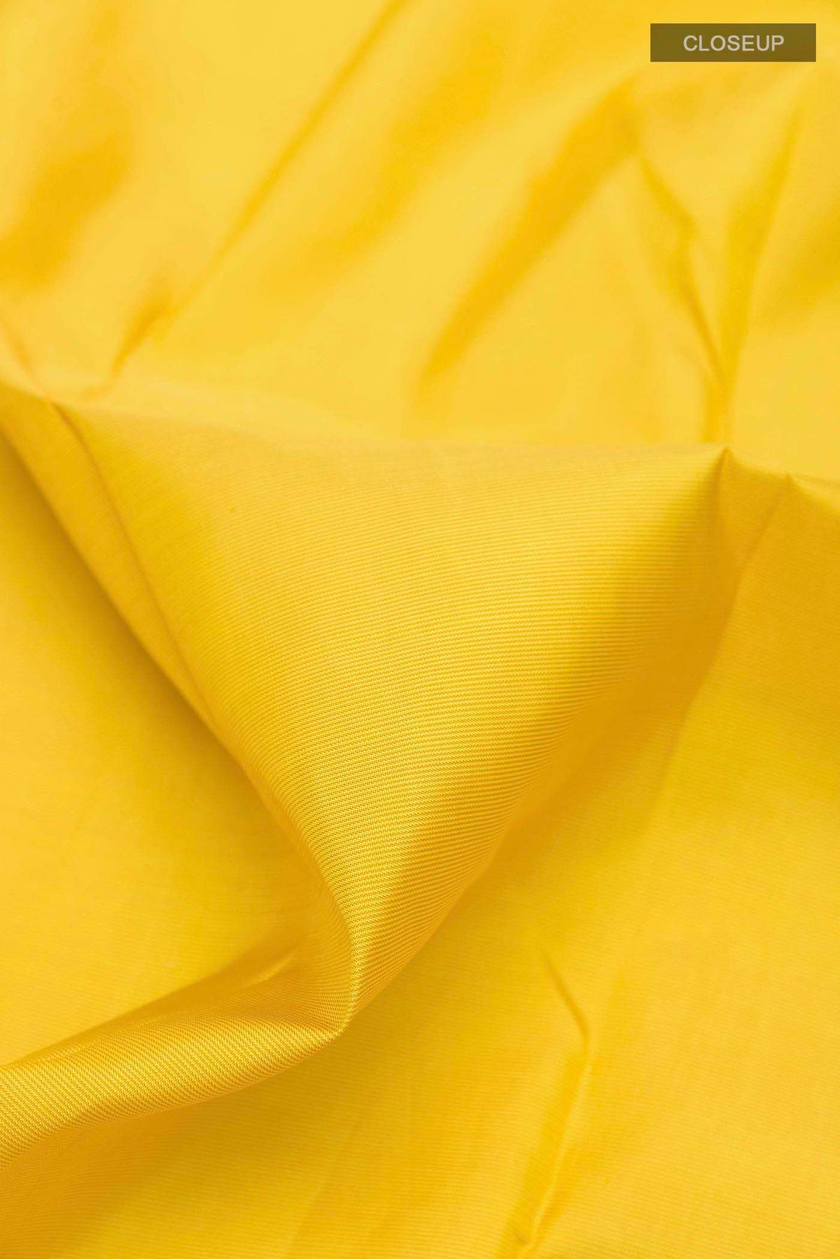 Close up of Yellow Kanchipuram Silk Saree with Zari Butta on the body and Ganga Jamuna Border displaying folds