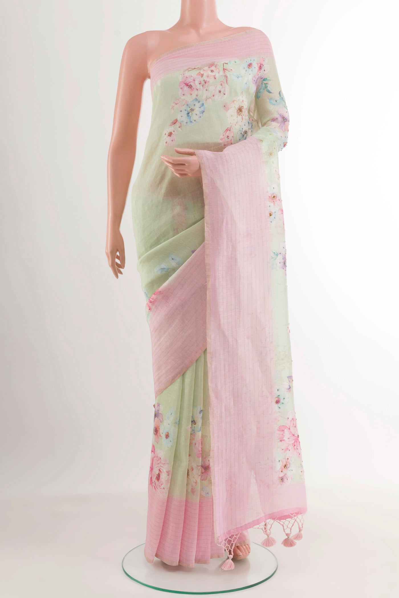 Green Linen Saree with Printed design on the body and Zari Border.  displayed on a mannequin