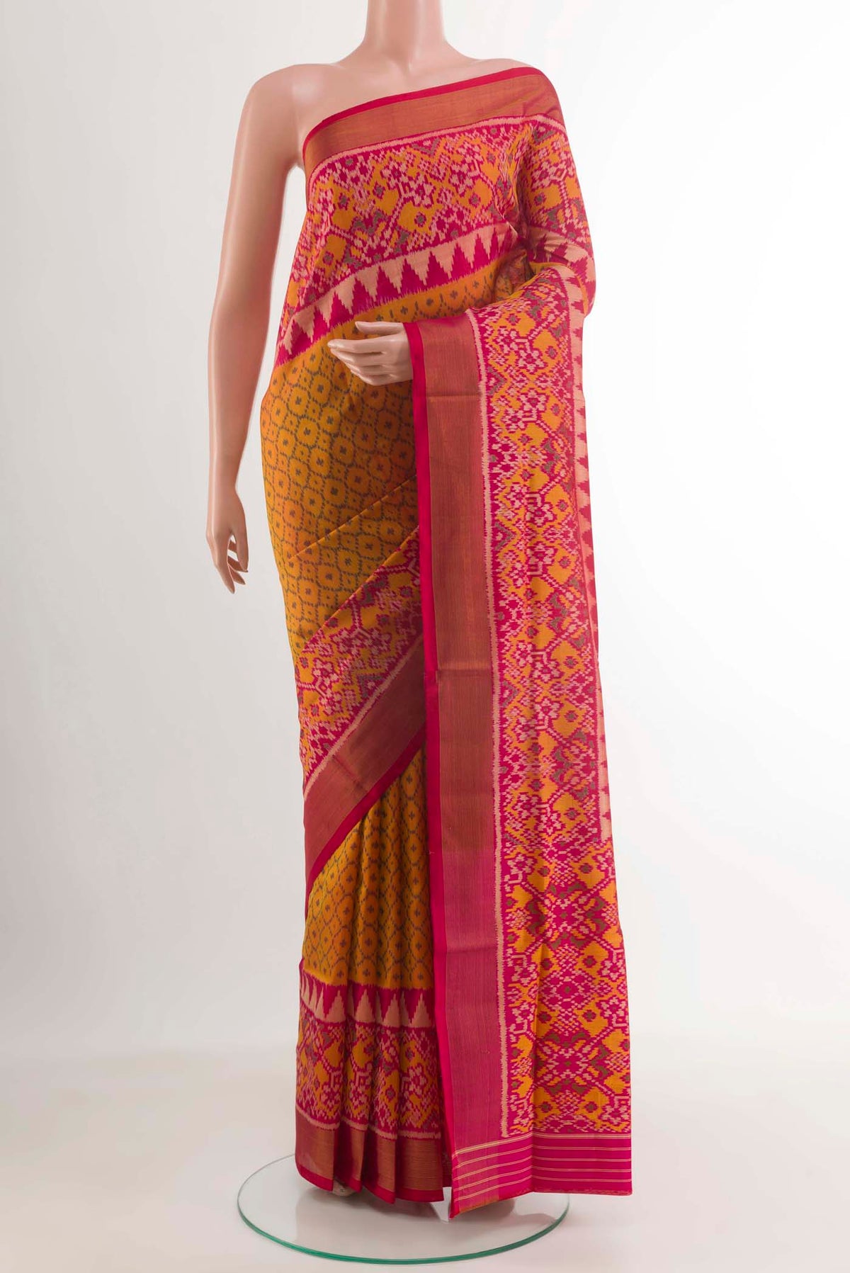 Mustard Rajkot Patola Silk Saree with Ikat design on the body and Zari Border.  displayed on a mannequin