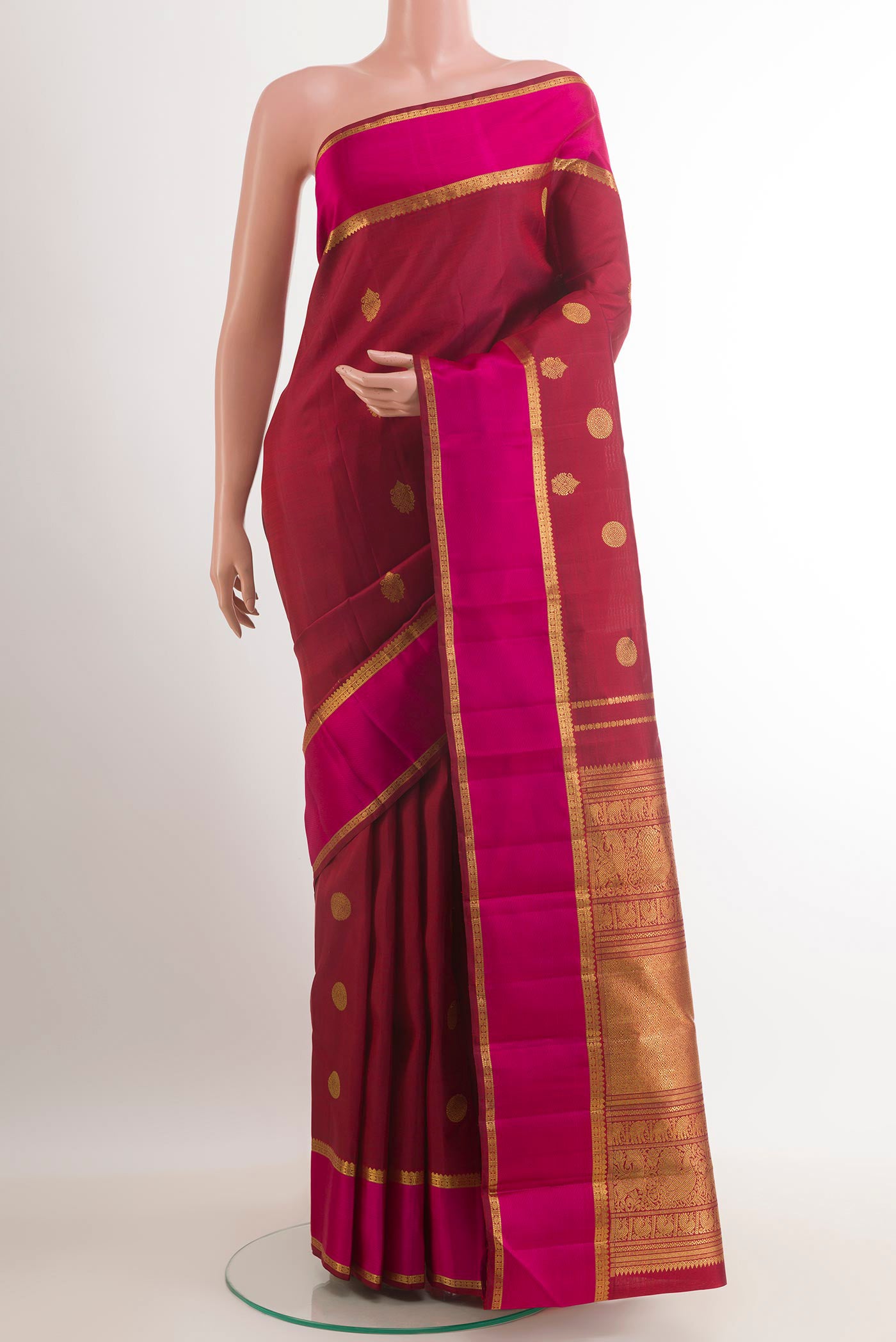 Maroon Kanjivaram Silk Saree with Zari Butta on the body and Zari Border.  displayed on a mannequin