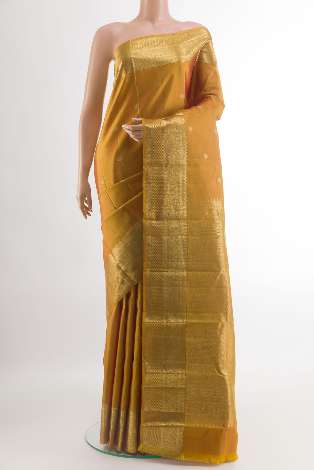 Mustard Kanchipuram Silk Saree with Zari Butta on the body and Zari Border.  displayed on a mannequin