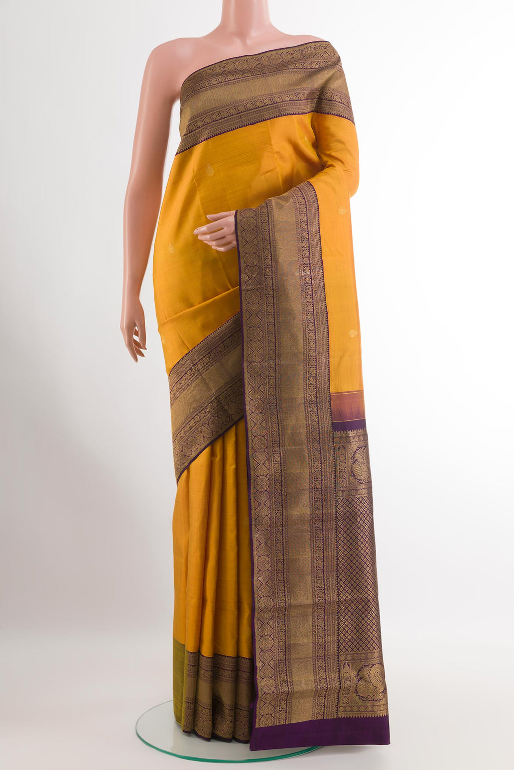 Mustard Kanchipuram Silk Saree with Zari Butta on the body and Zari Border.  displayed on a mannequin