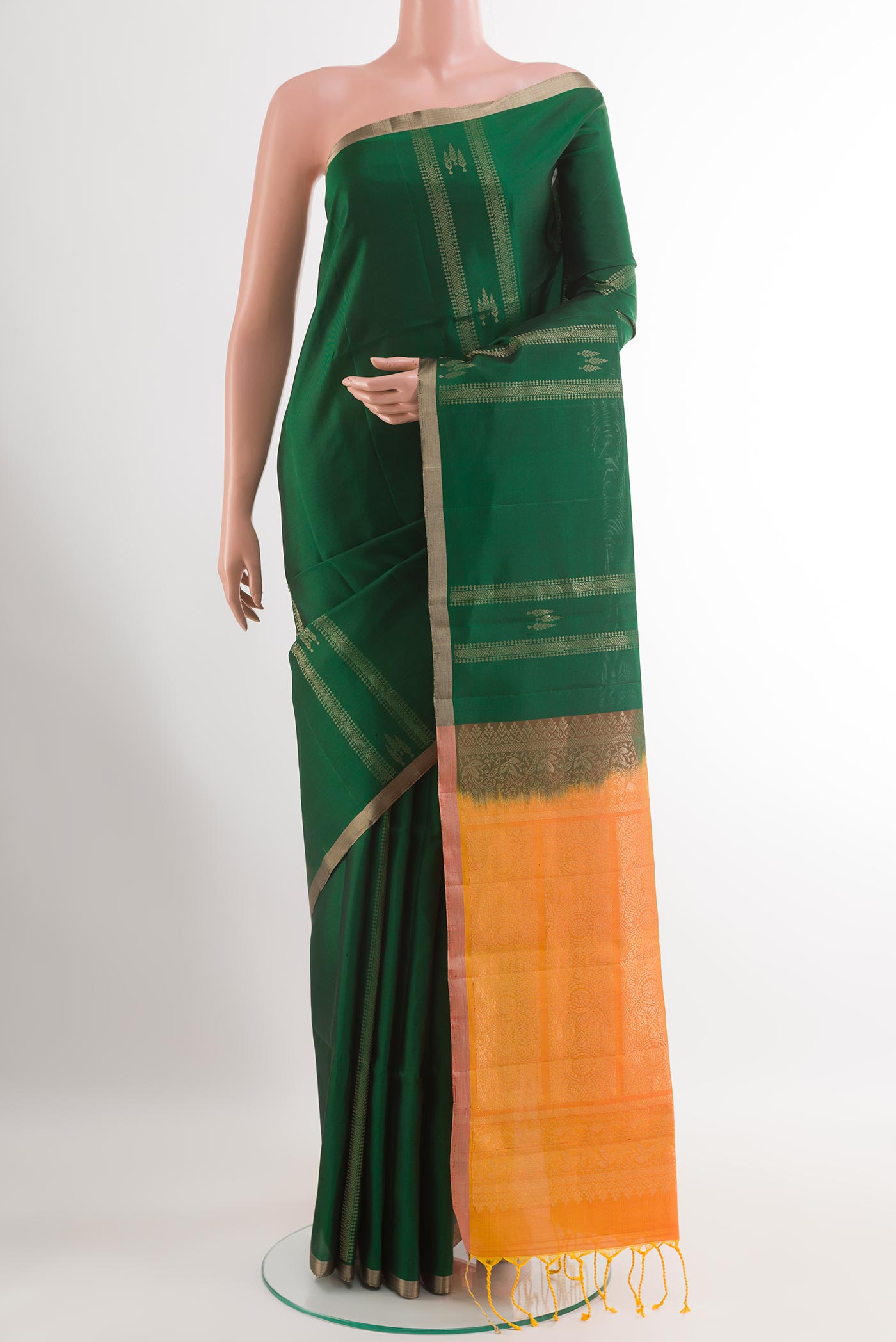 Bottle Green Soft Silk Saree with Zari Butta on the body and Zari Border.  displayed on a mannequin