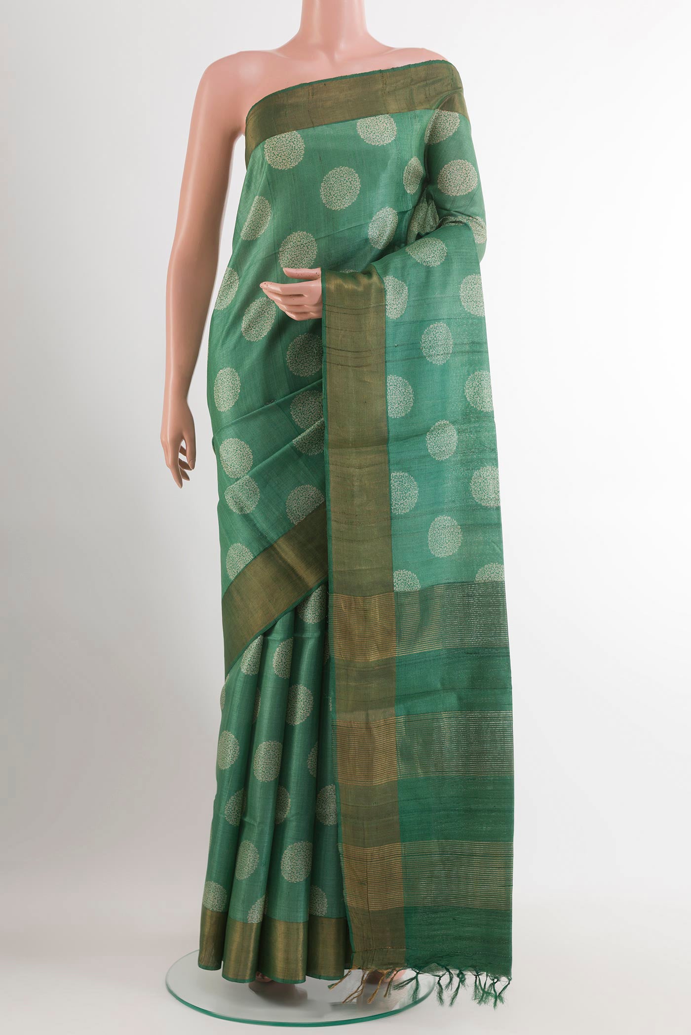 Green Tussar Saree with Printed design on the body and Zari Border.  displayed on a mannequin