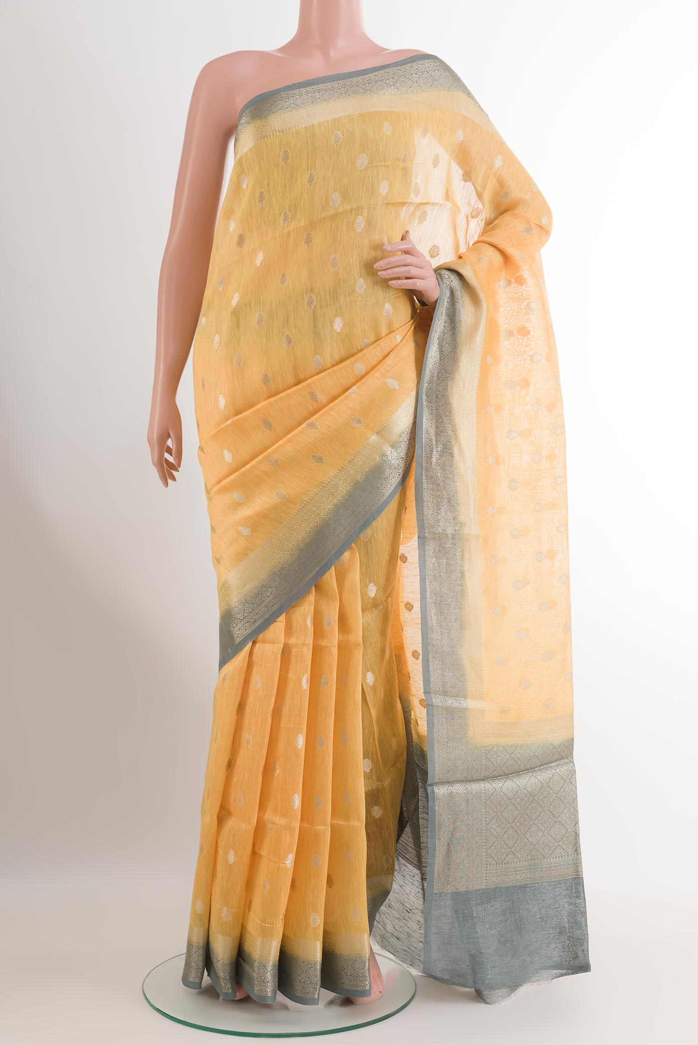 Yellow Linen Saree with Zari Butta on the body and Zari Border.  displayed on a mannequin