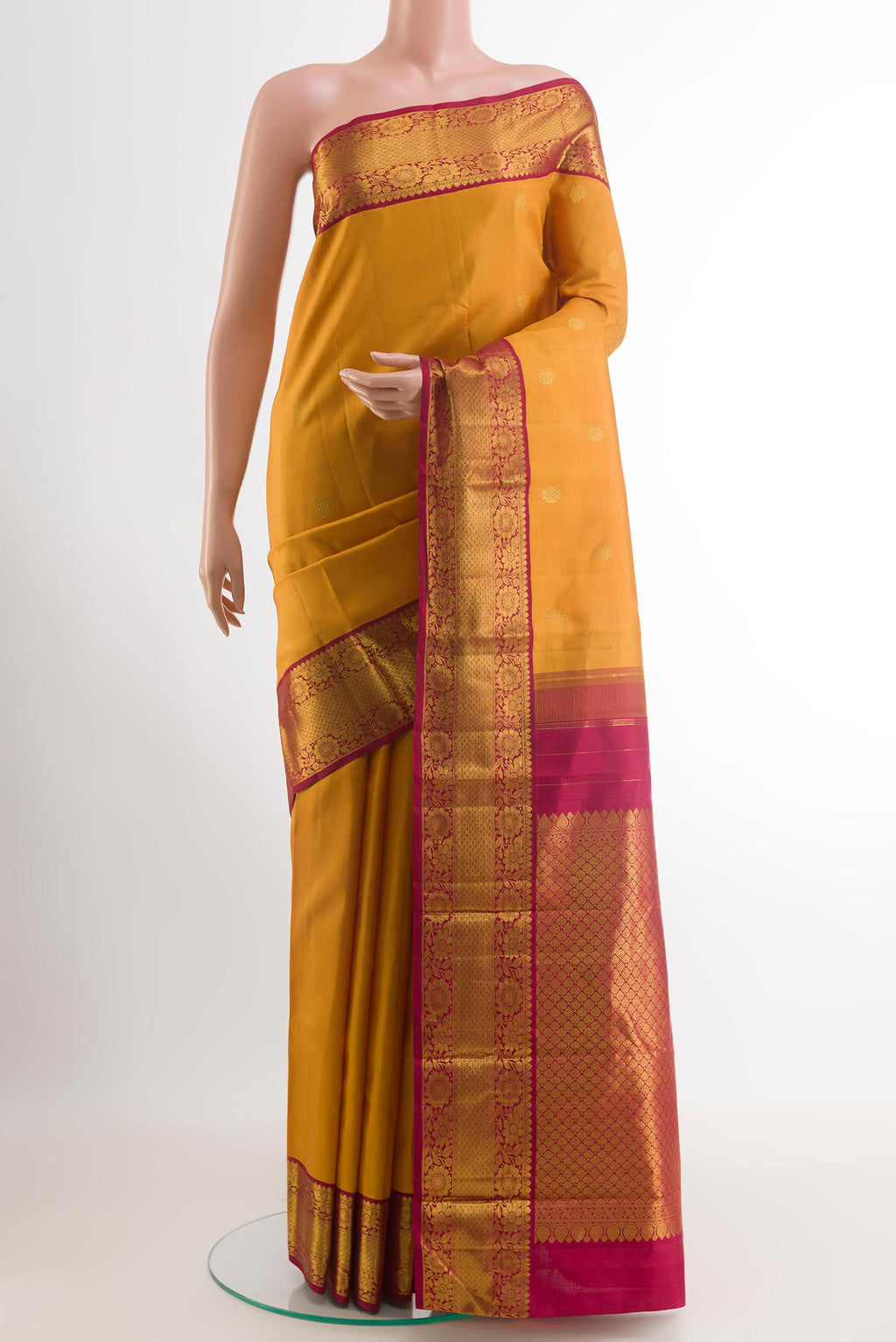 Mustard Kanjivaram Silk Saree with Zari Butta on the body and Zari Border.  displayed on a mannequin