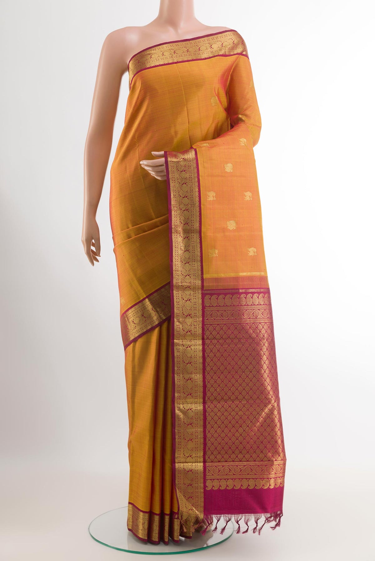 Mustard Kanjivaram Silk Saree with Zari Butta on the body and Zari Border.  displayed on a mannequin