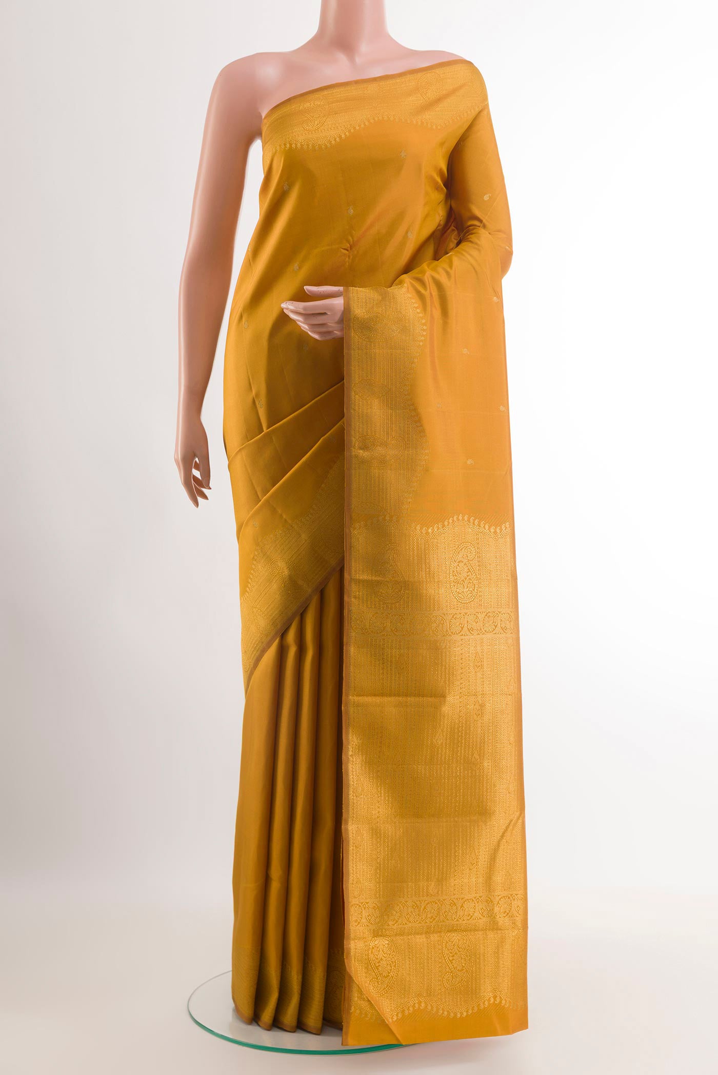Mustard Kanjivaram Silk Saree with Zari Butta on the body and Zari Border.  displayed on a mannequin