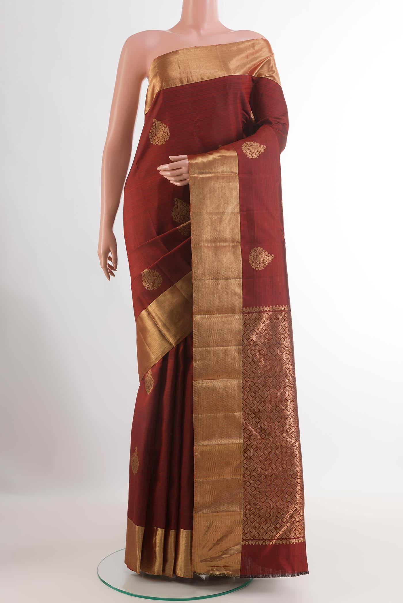 Maroon Kanchipuram Silk Saree with Zari Butta on the body and Zari Border.  displayed on a mannequin