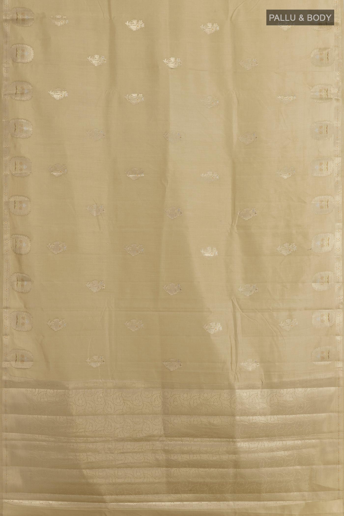 Flat view of Beige Tussar Silk Saree with Zari Butta on the body and Zari Border. 