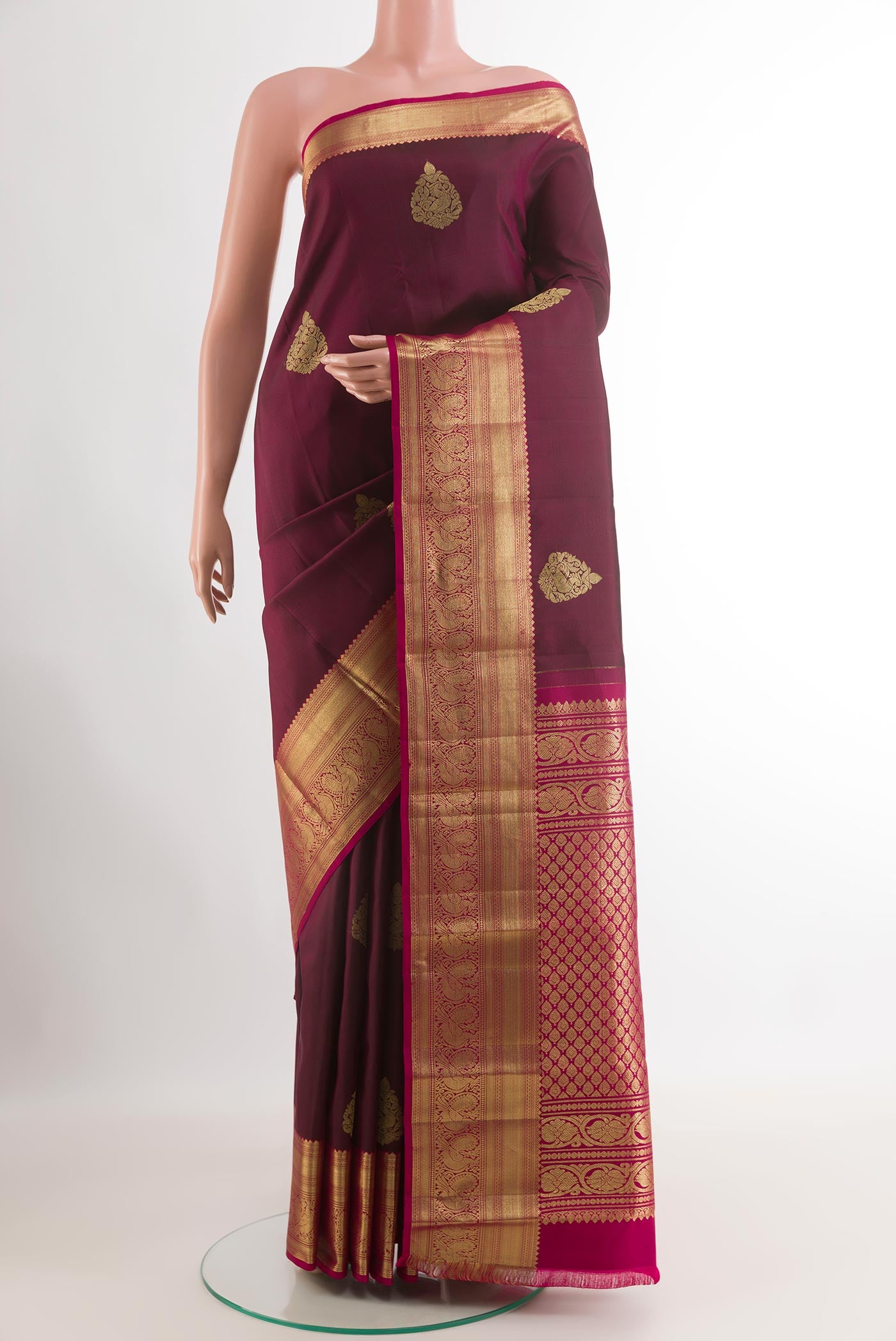 Maroon Kanchipuram Silk Saree with Zari Butta on the body and Zari Border.  displayed on a mannequin