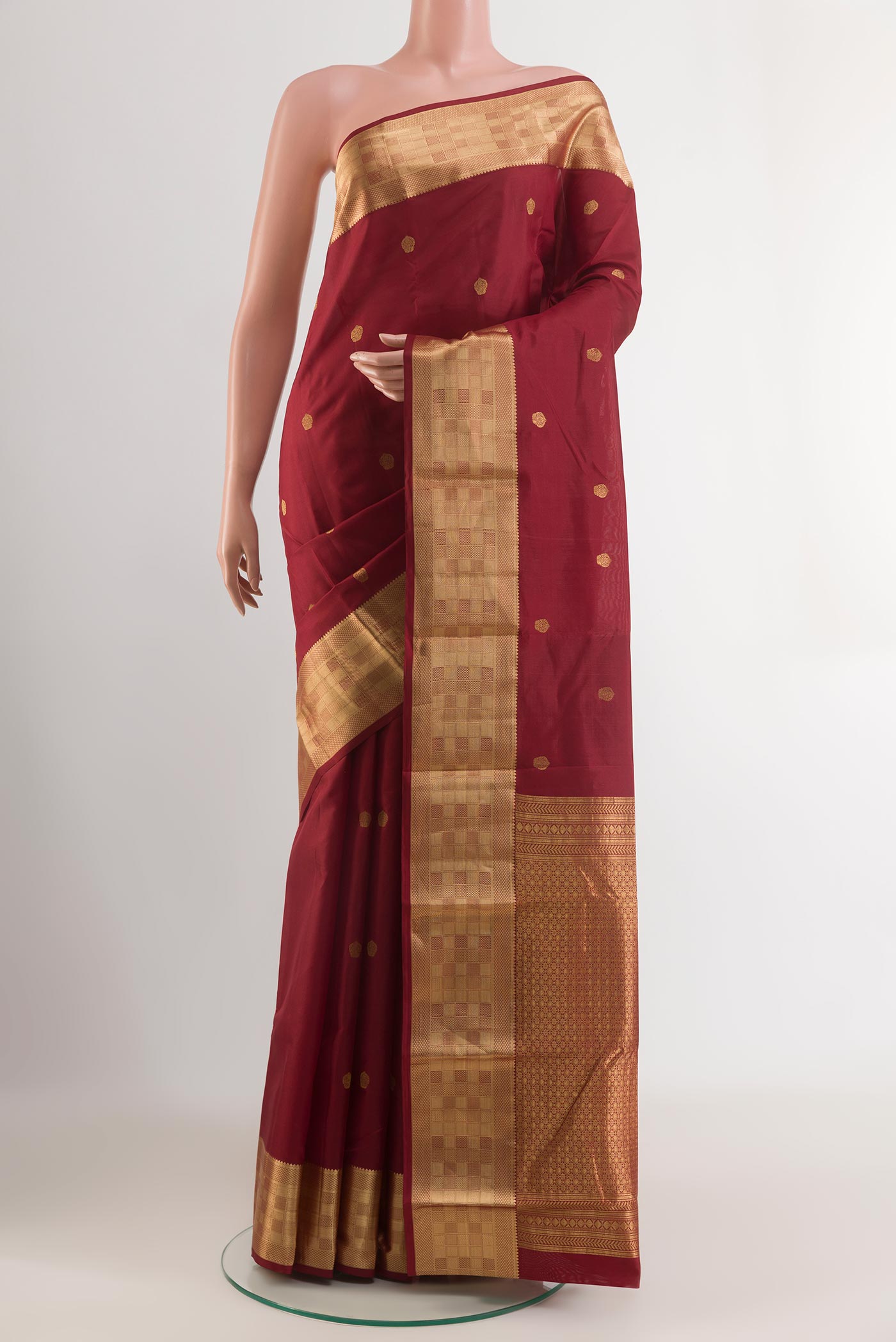 Maroon Kanchipuram Silk Saree with Zari Butta on the body and Zari Border.  displayed on a mannequin