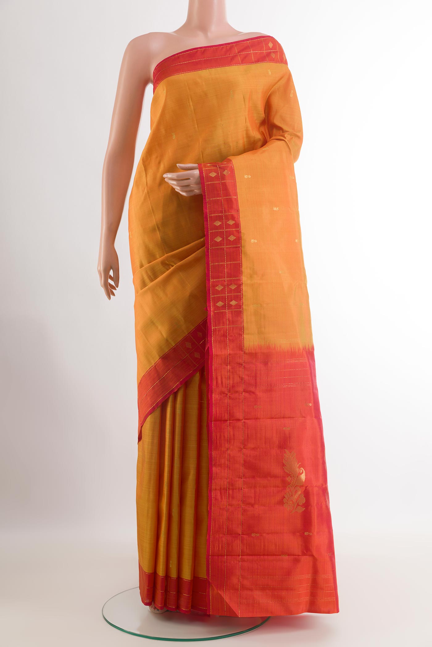 Mustard Kanchipuram Silk Saree with Zari Butta on the body and Zari Border.  displayed on a mannequin