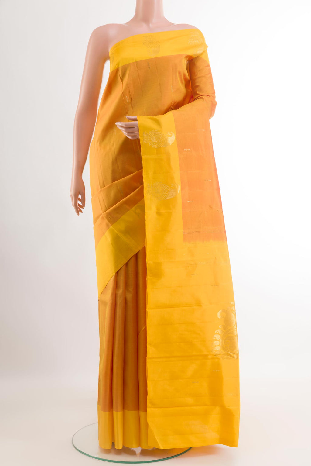Mustard Kanchipuram Silk Saree with Zari Butta on the body and Zari Border.  displayed on a mannequin