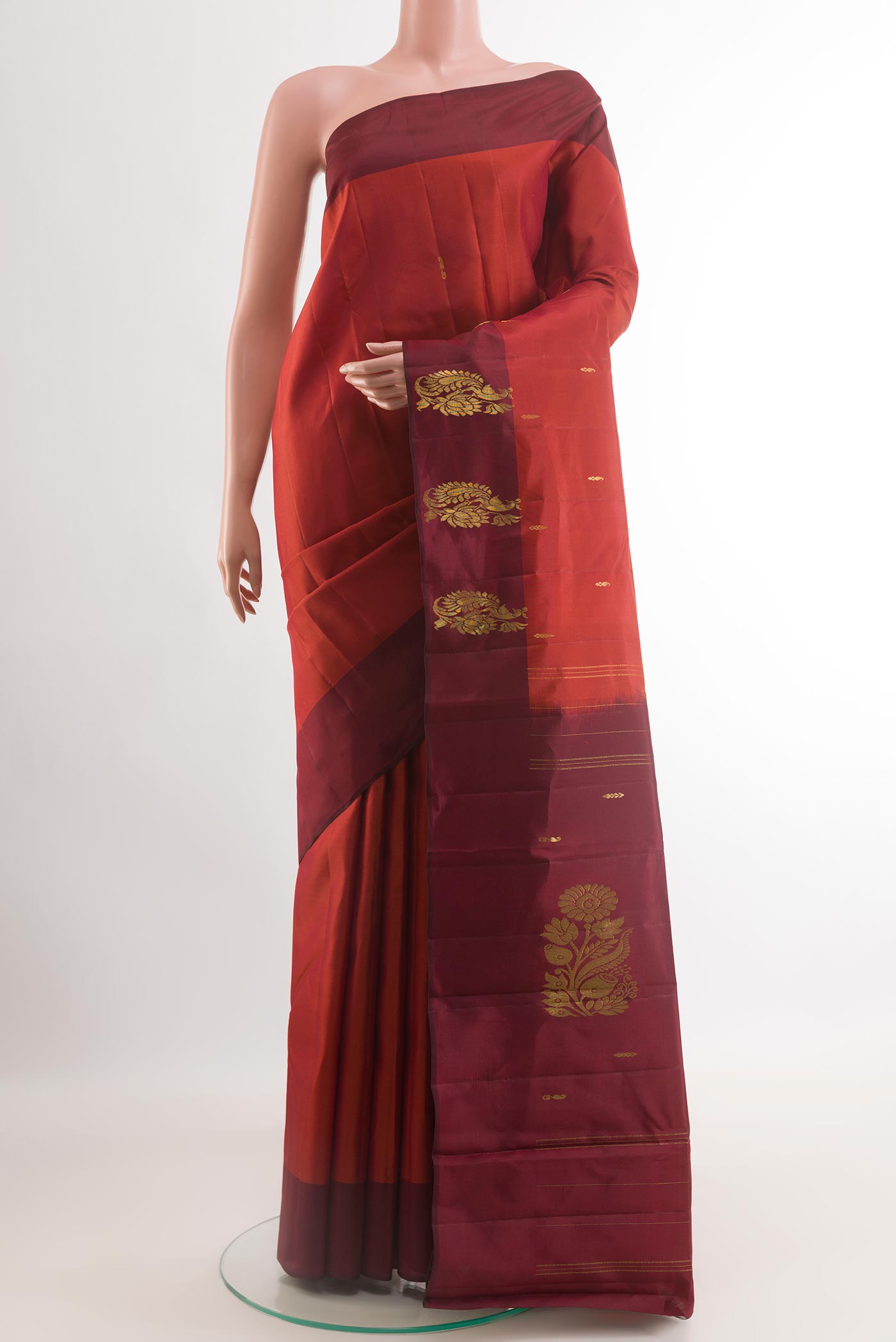 Rust Kanchipuram Silk Saree with Zari Butta on the body and Zari Border.  displayed on a mannequin