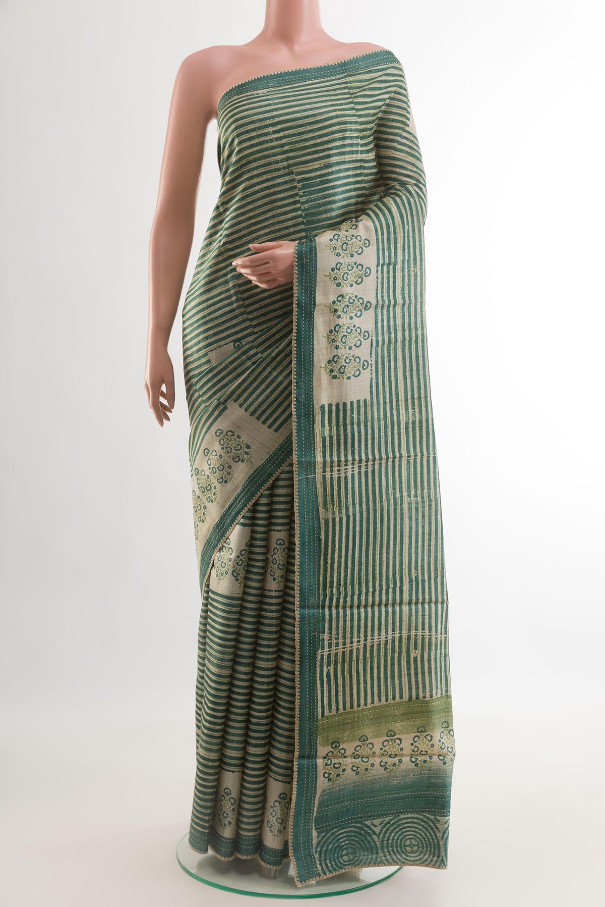 Green Tussar Silk Saree with Printed design on the body and Printed Border.  displayed on a mannequin