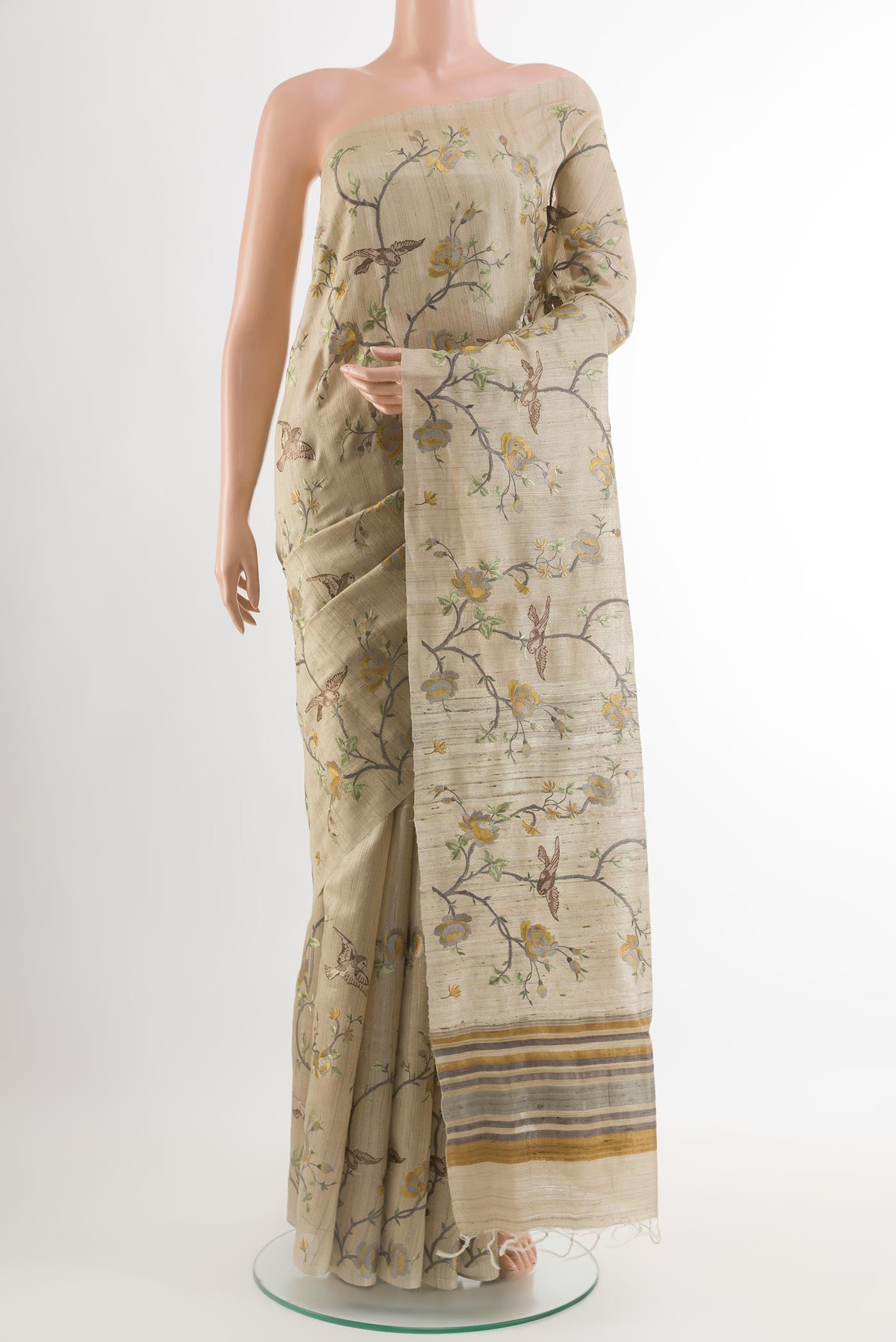 Beige Tussar Saree with Embroidery on the body and Embroidery Border.  displayed on a mannequin