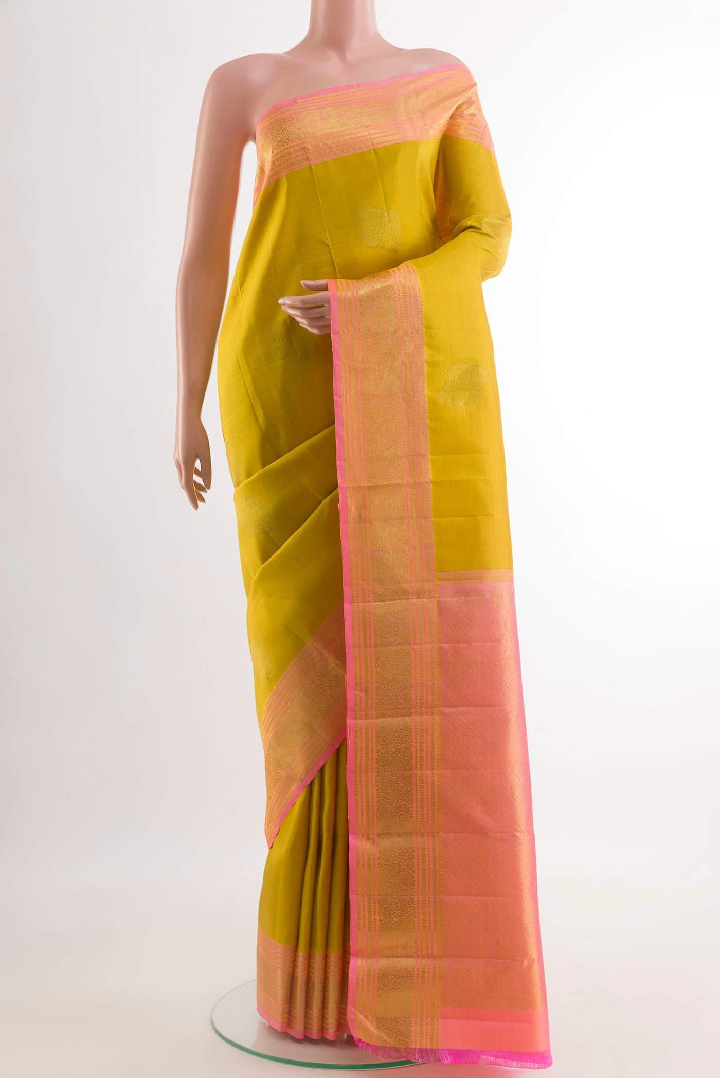 Mustard Kanchipuram Silk Saree with Zari Butta on the body and Zari Border.  displayed on a mannequin