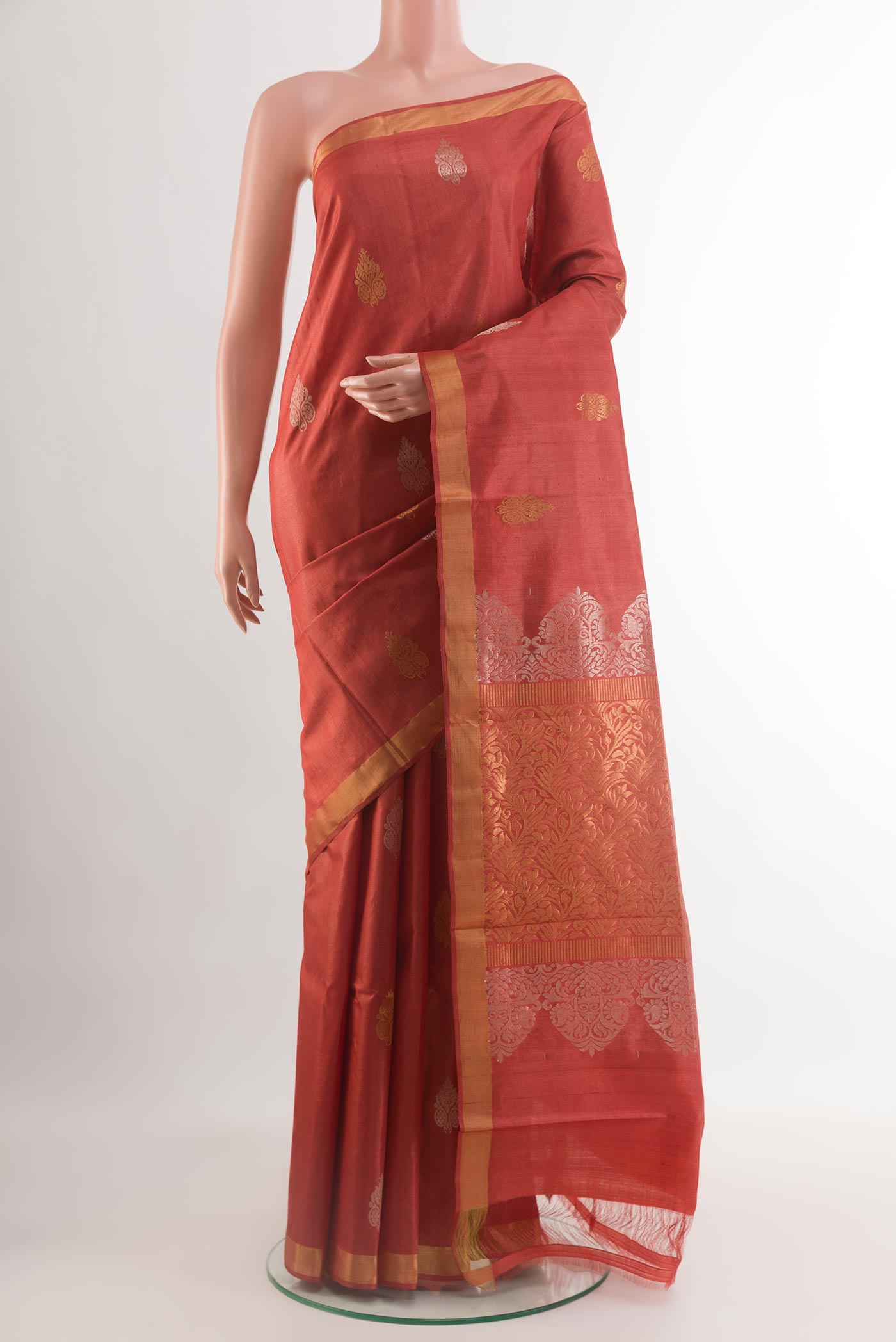 Rust Tussar Silk Saree with Zari Butta on the body and Zari Border.  displayed on a mannequin