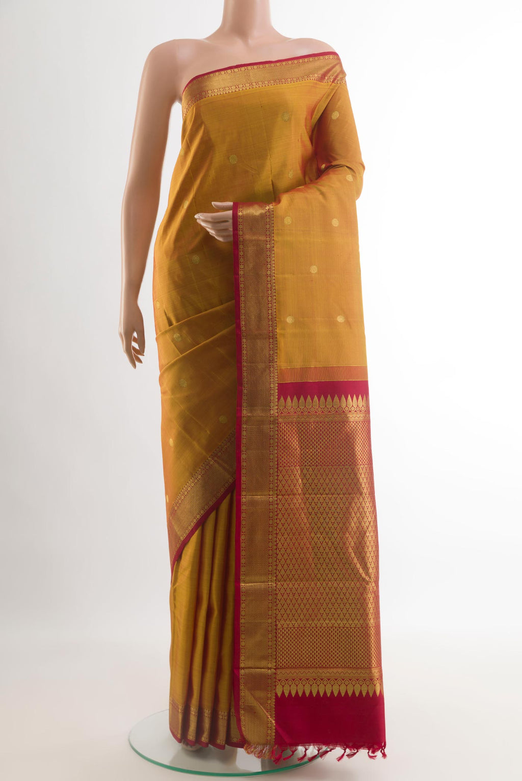 Mustard Kanjivaram Silk Saree with Zari Butta on the body and Zari Border.  displayed on a mannequin
