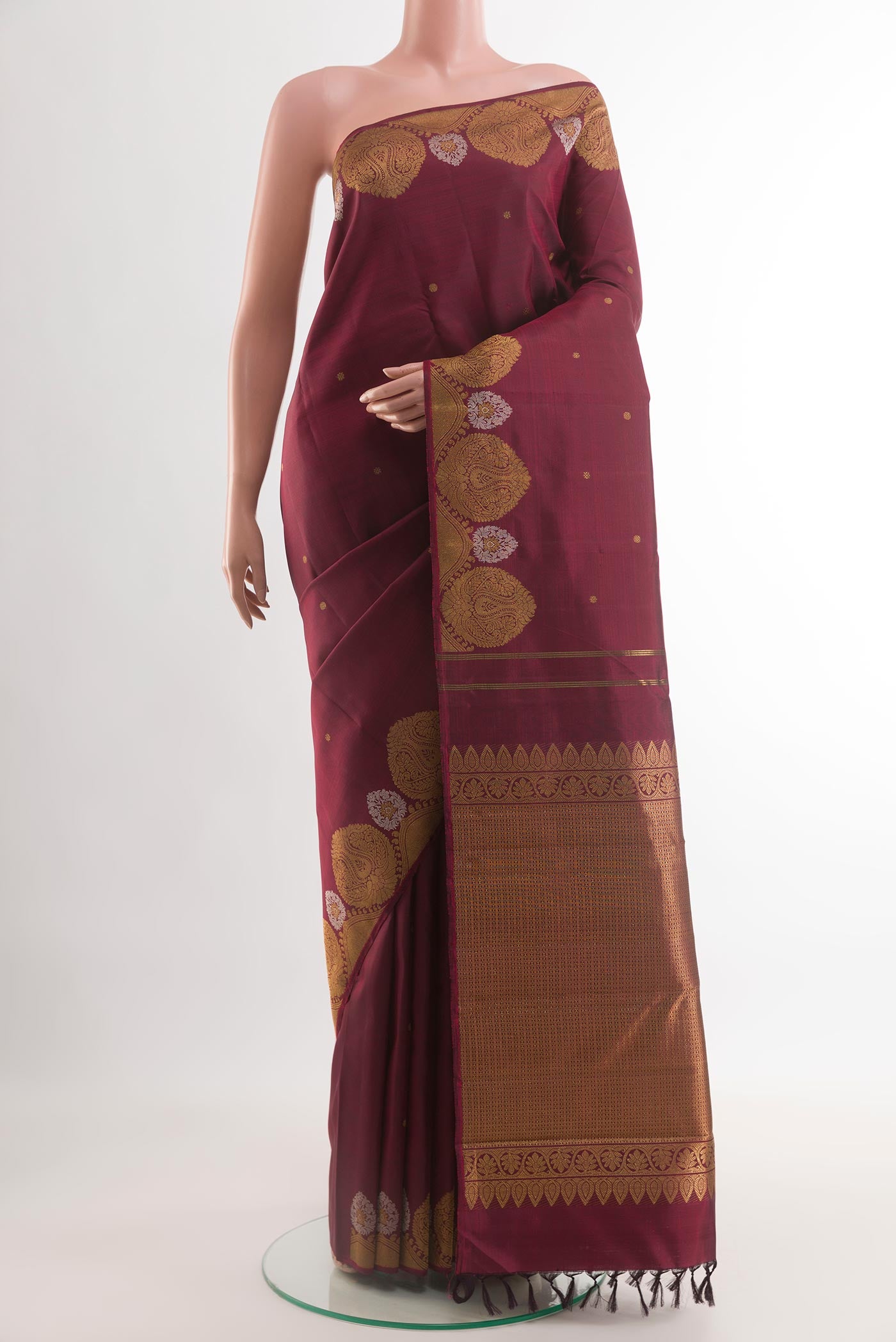Maroon Kanchipuram Silk Saree with Zari Butta on the body and Zari Border.  displayed on a mannequin