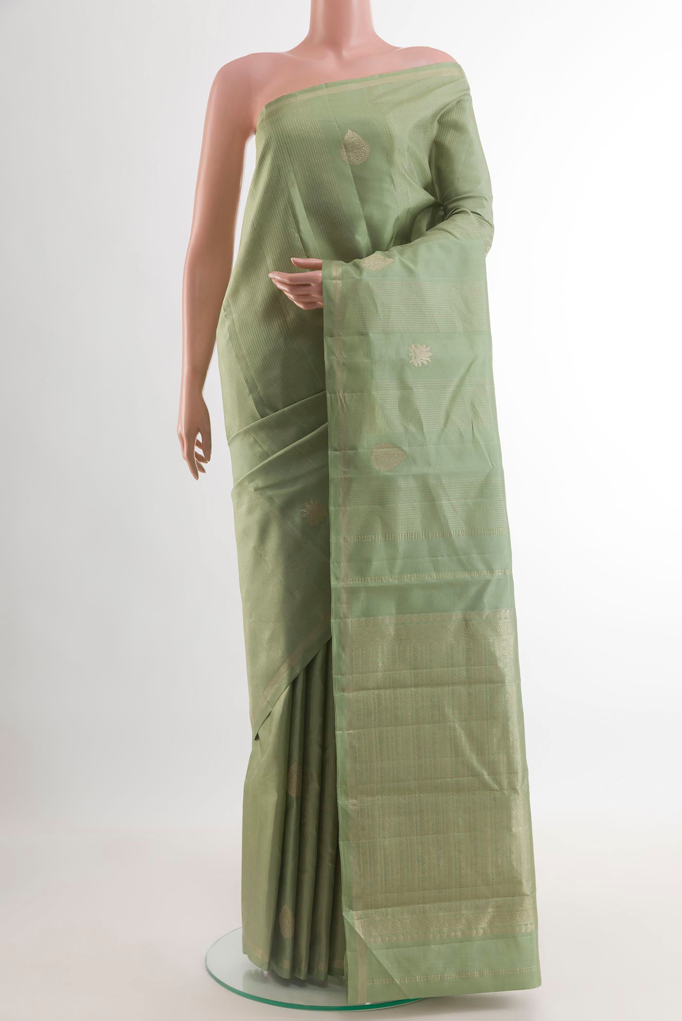 Sage Green Kanchipuram Silk Saree with Zari Butta on the body and Thin Zari Line.  displayed on a mannequin