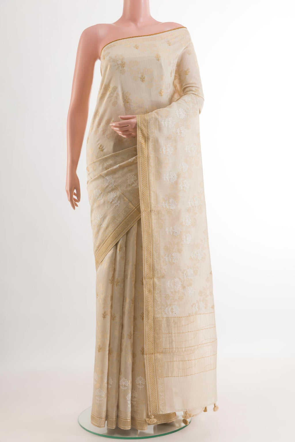 Cream Tussar Silk Saree with Embroidery on the body and Zari Border.  displayed on a mannequin