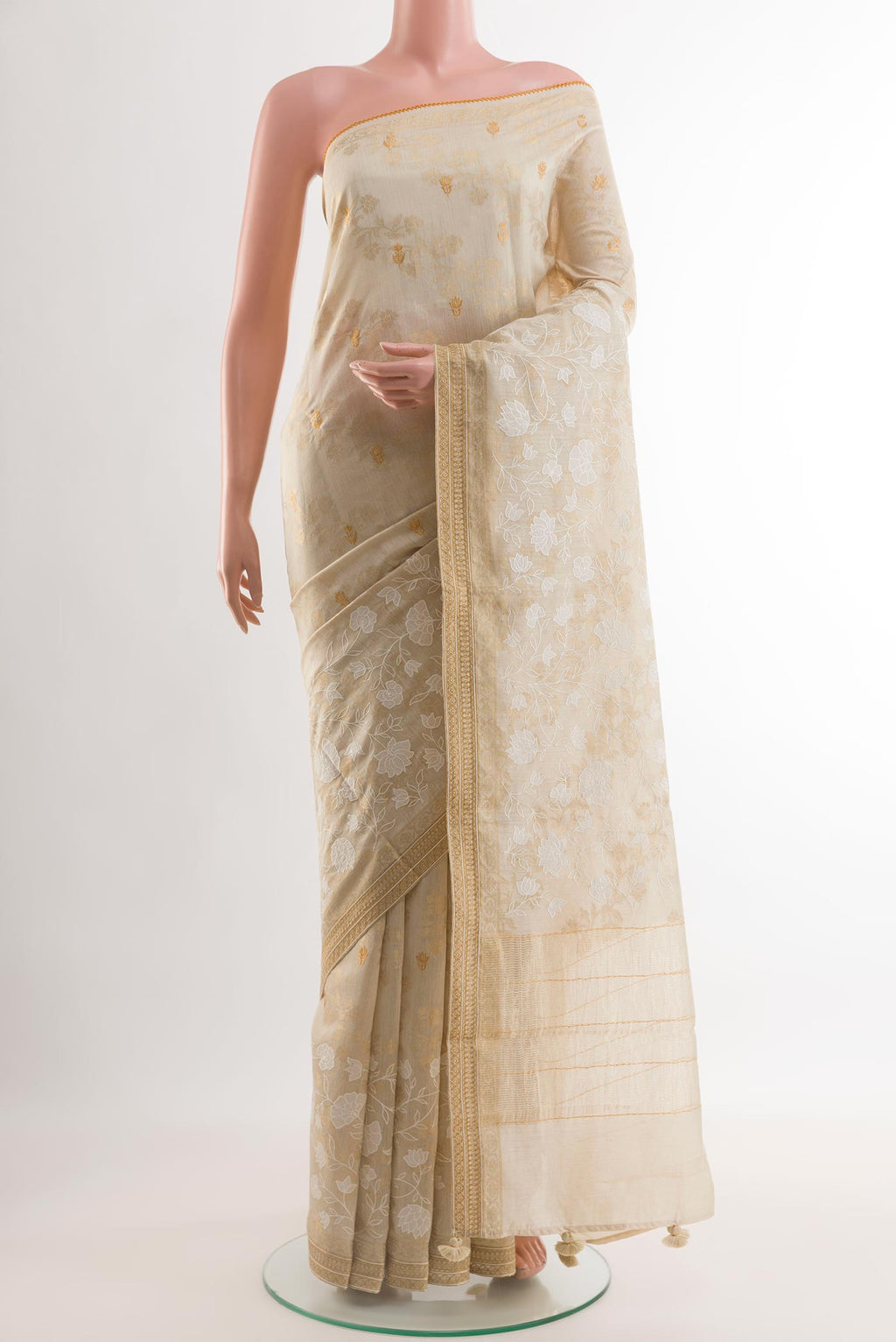 Cream Tussar Silk Saree with Embroidery on the body and Zari Border.  displayed on a mannequin