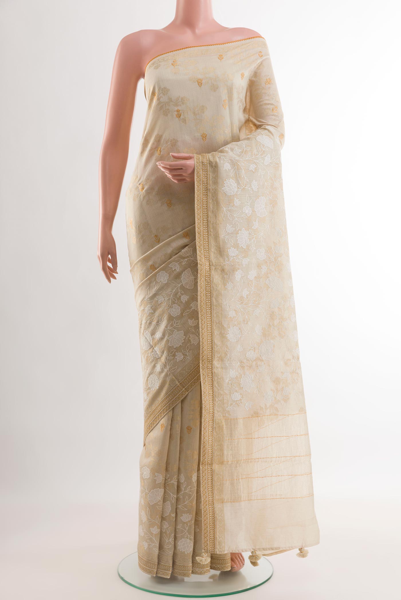 Cream Tussar Silk Saree with Embroidery on the body and Zari Border.  displayed on a mannequin