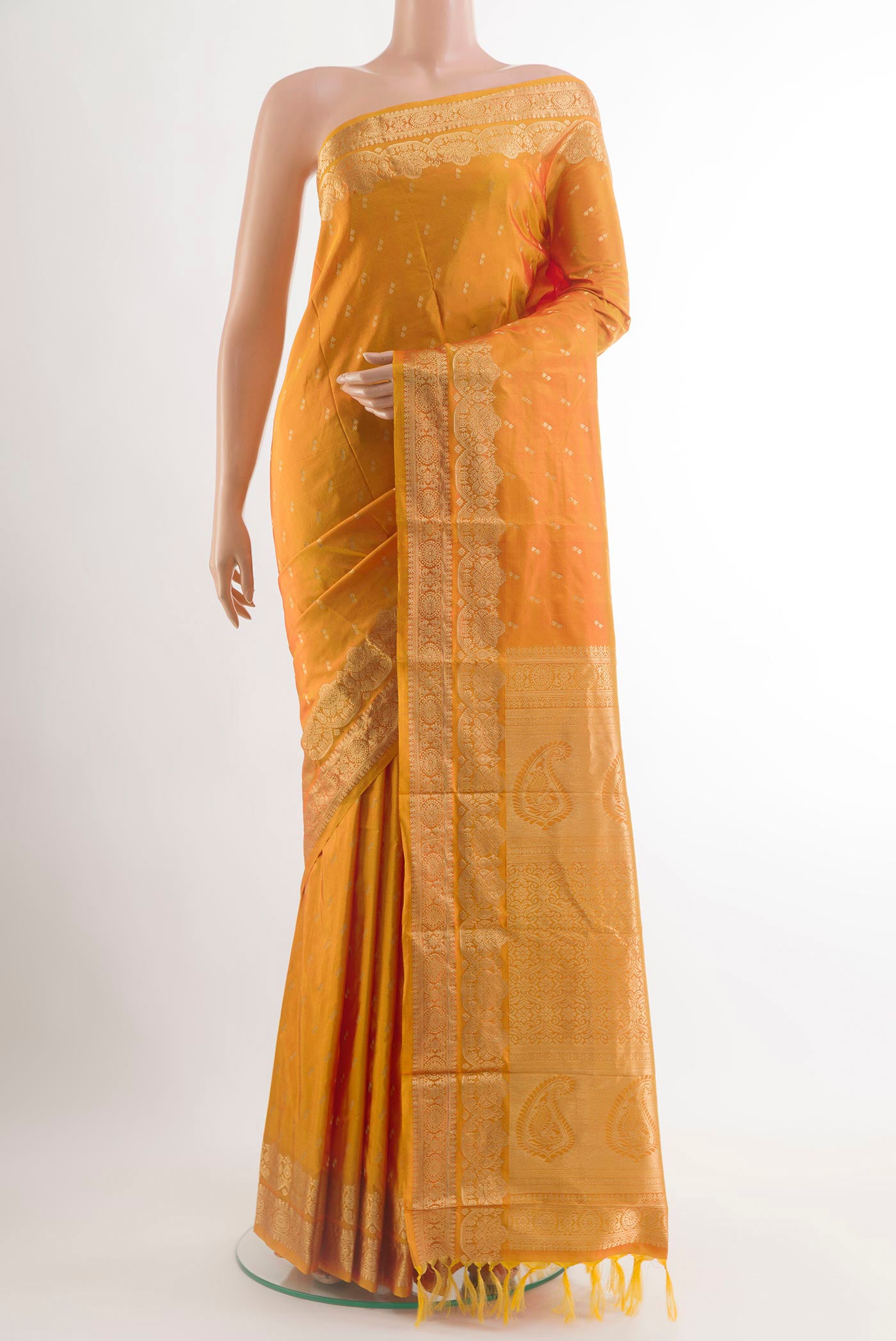 Mustard Kanjivaram Silk Saree with Zari Butta on the body and Zari Border.  displayed on a mannequin