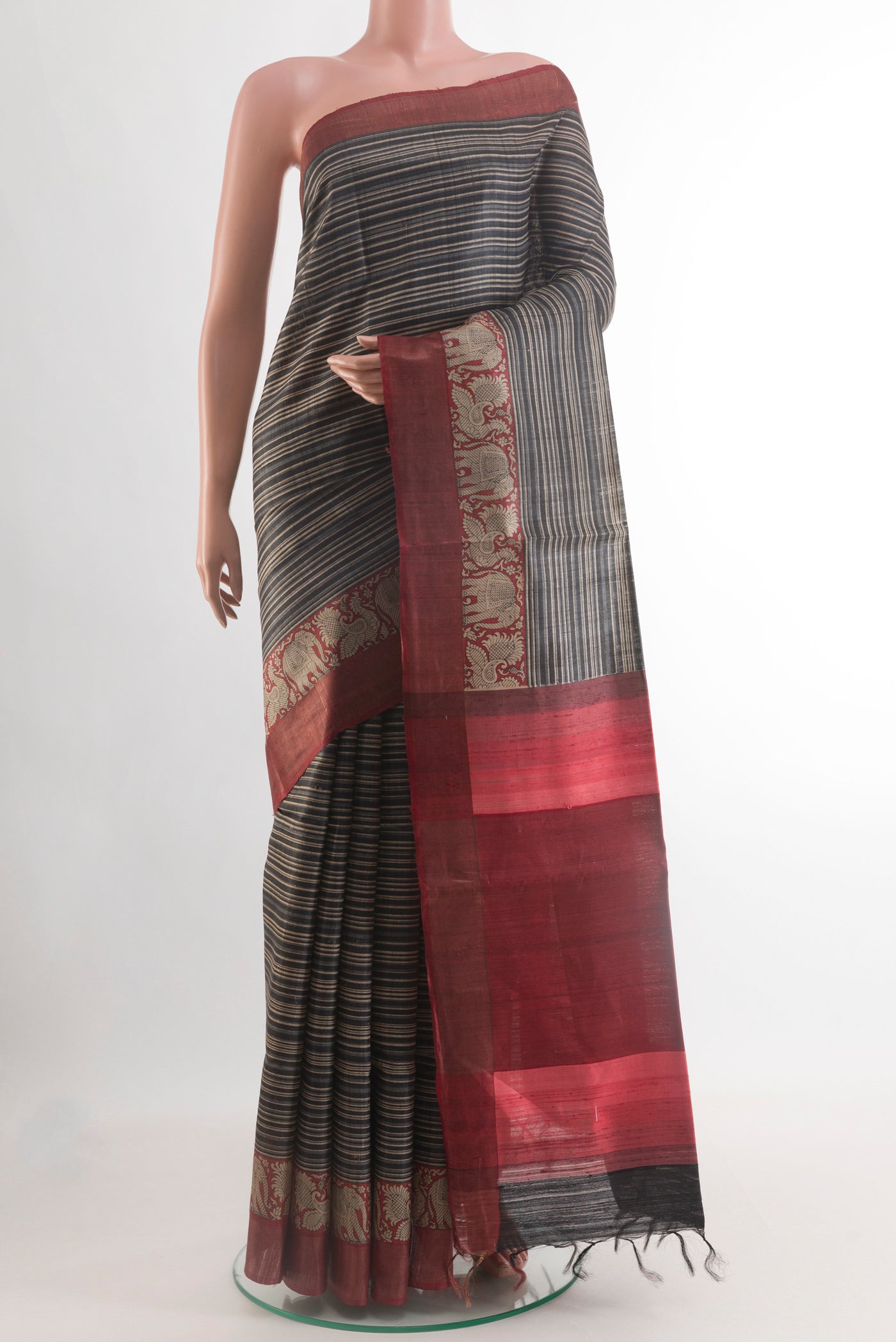 Black Tussar Silk Saree with Printed design on the body and Zari Border.  displayed on a mannequin