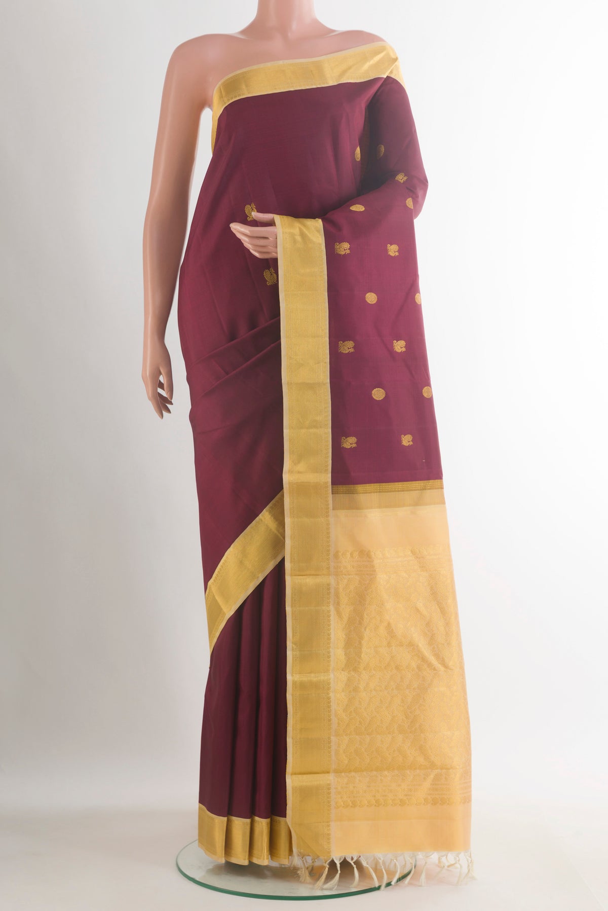 Pure Silk Maroon Kanjivaram Saree with Zari Butta on the body and Zari Border.  displayed on a mannequin