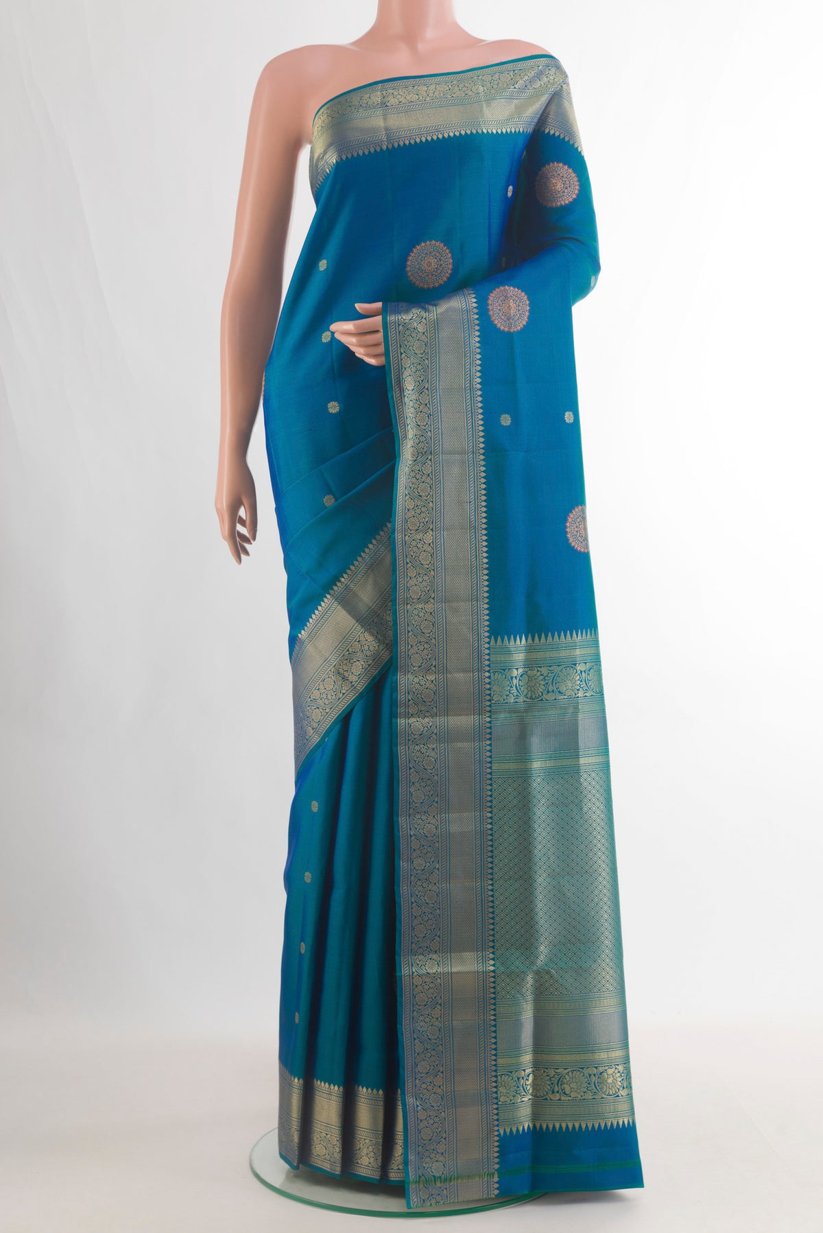 Pure Silk Peacock Blue Soft Saree with Zari Butta on the body and Zari Border.  displayed on a mannequin
